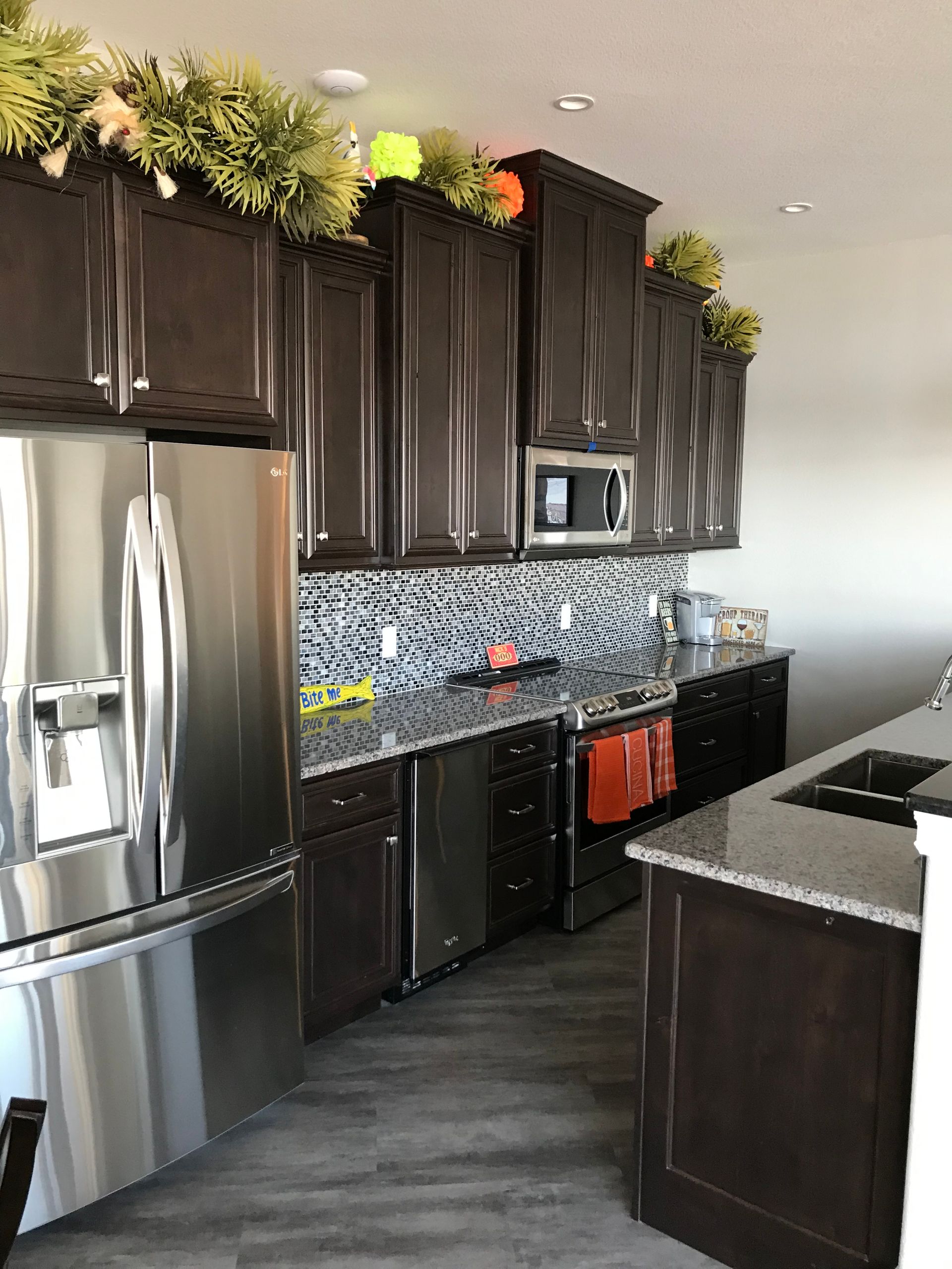 Modern kitchen with dark cabinets, stainless steel fridge, and granite island countertops