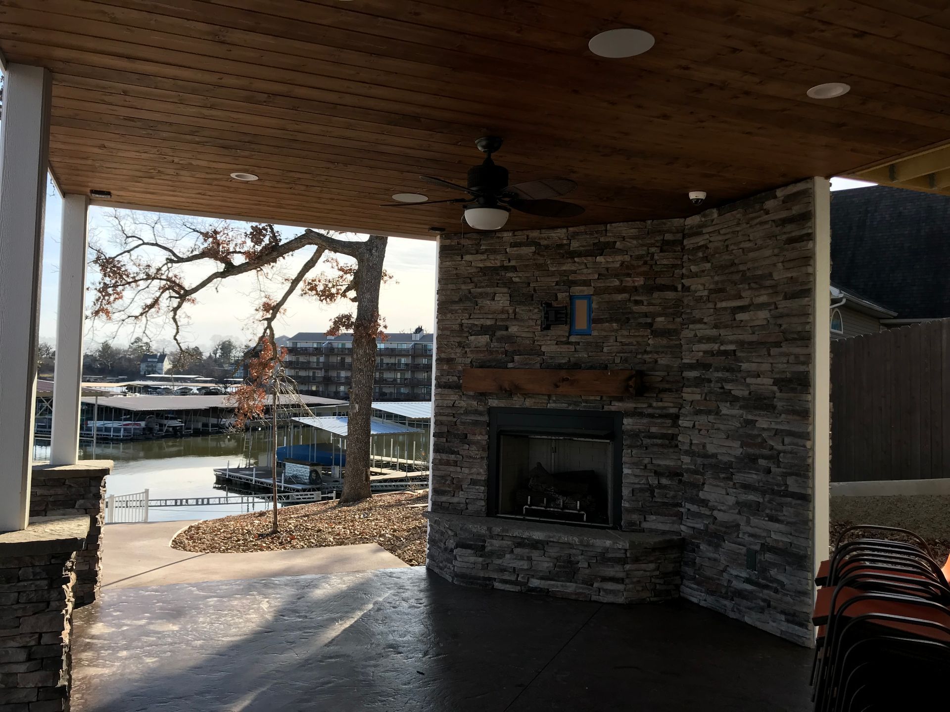 Covered patio with stone fireplace, wooden ceiling, and a view of the water through open sides