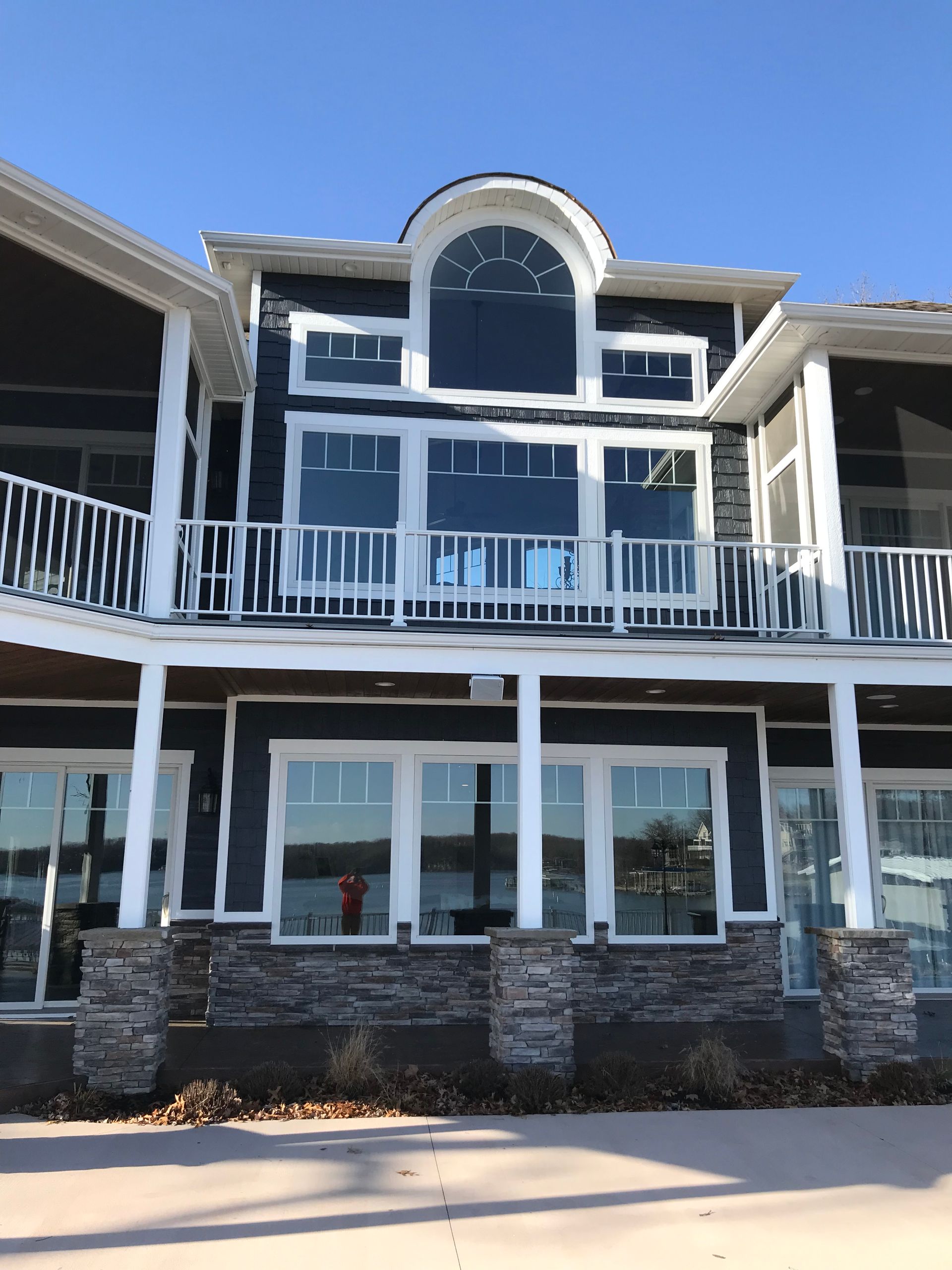 Three-story building with blue siding, white balconies, and a stone base under a bright sky