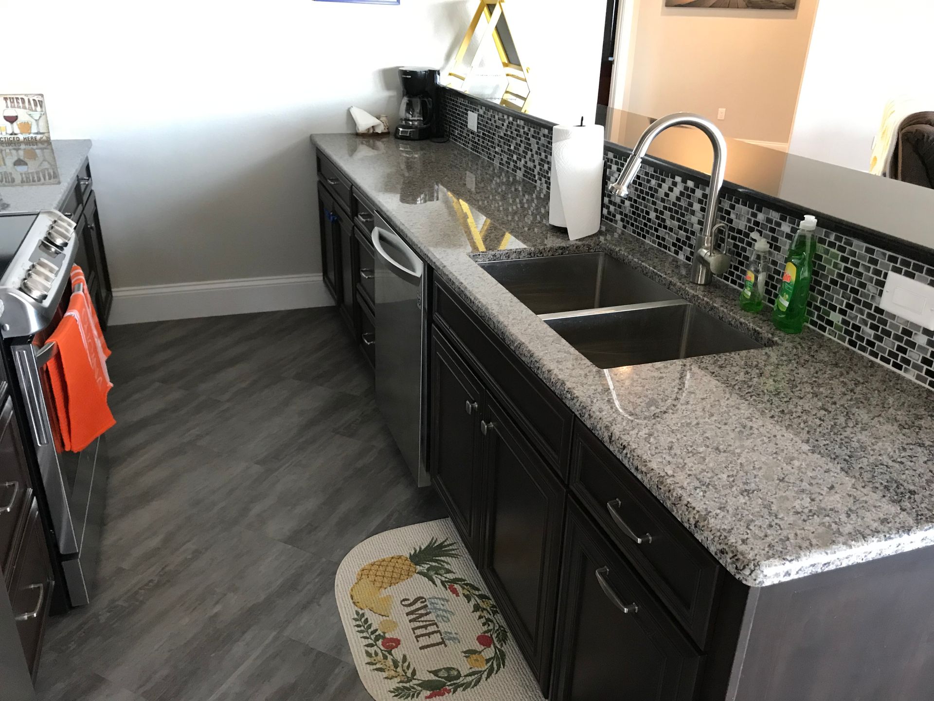 Modern kitchen with black cabinets, granite countertops, and stainless sink along a windowed wall