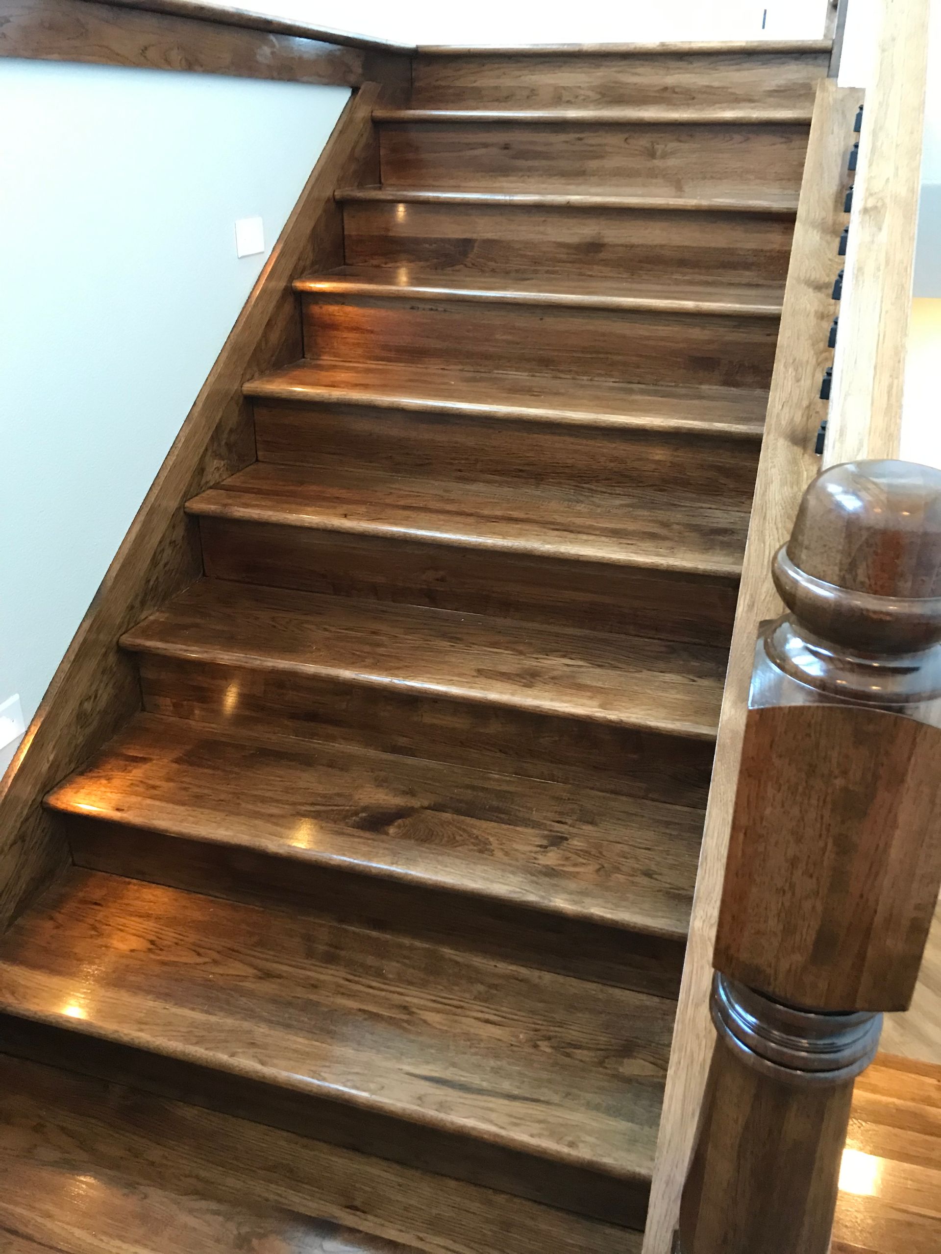 Wooden staircase with worn steps and a banister in a bright indoor hallway