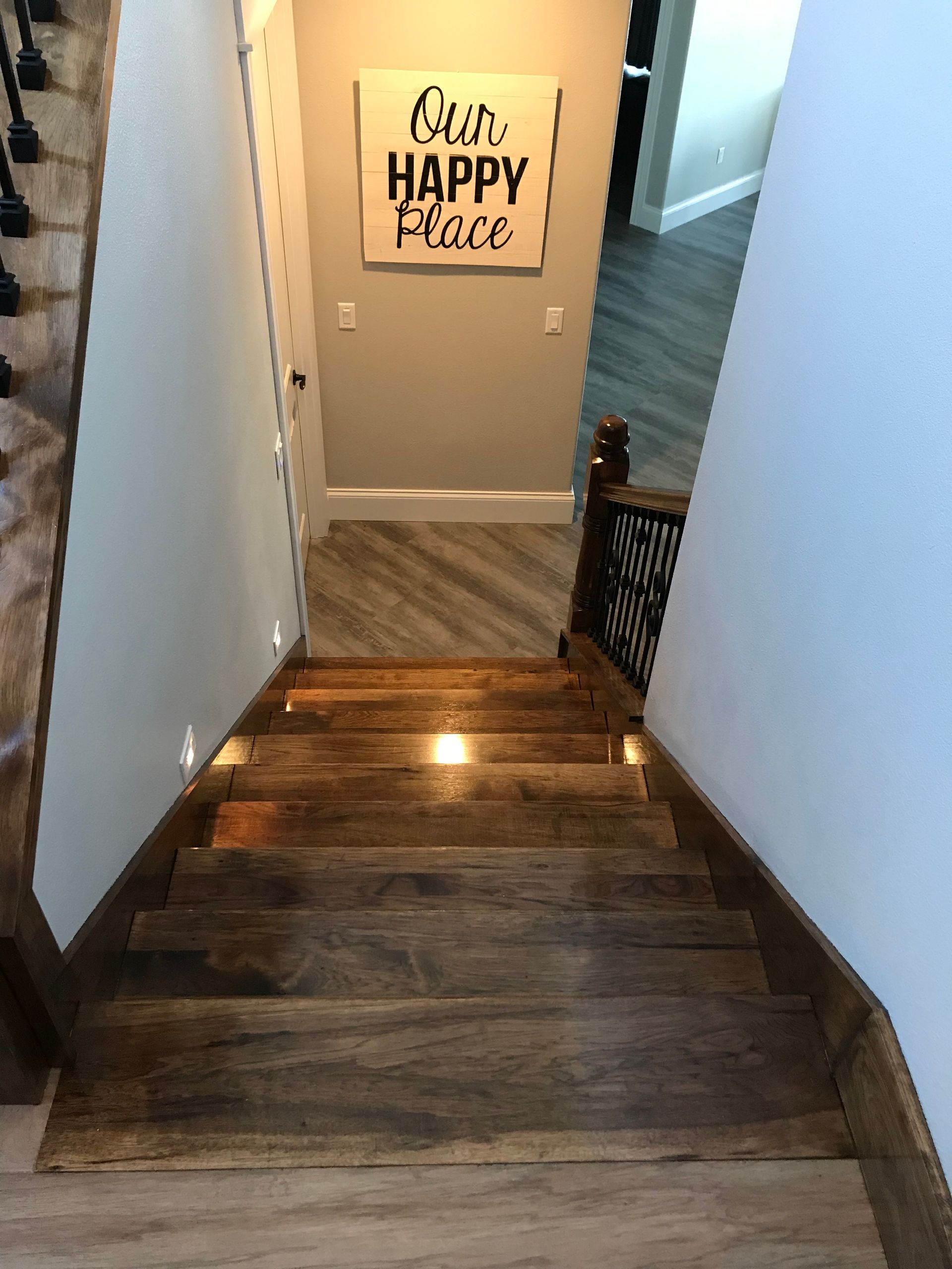 Narrow wooden staircase with a “Quit Happy Place” sign at the bottom.