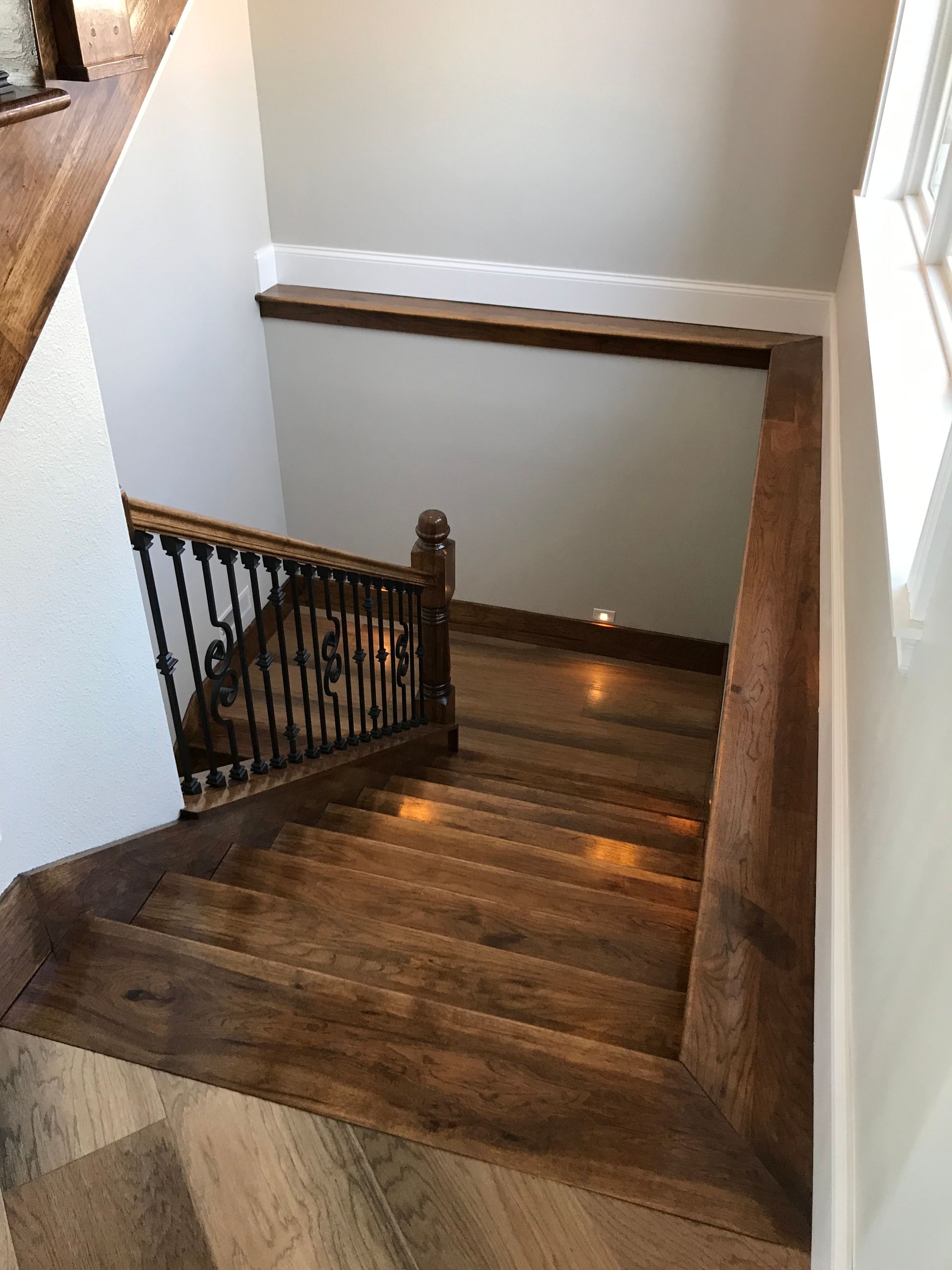 Wooden staircase with black railing descending to a lower level in a home.