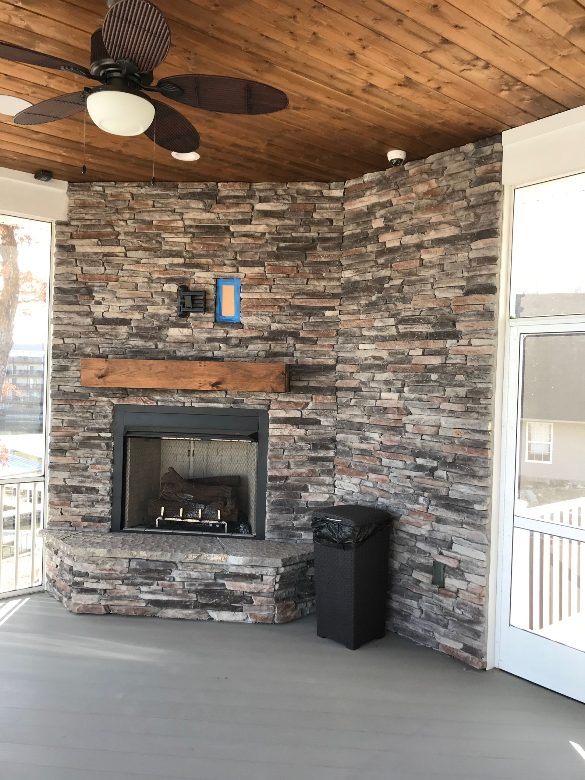 Covered porch with stone fireplace, wood ceiling, ceiling fan, and white screened doors
