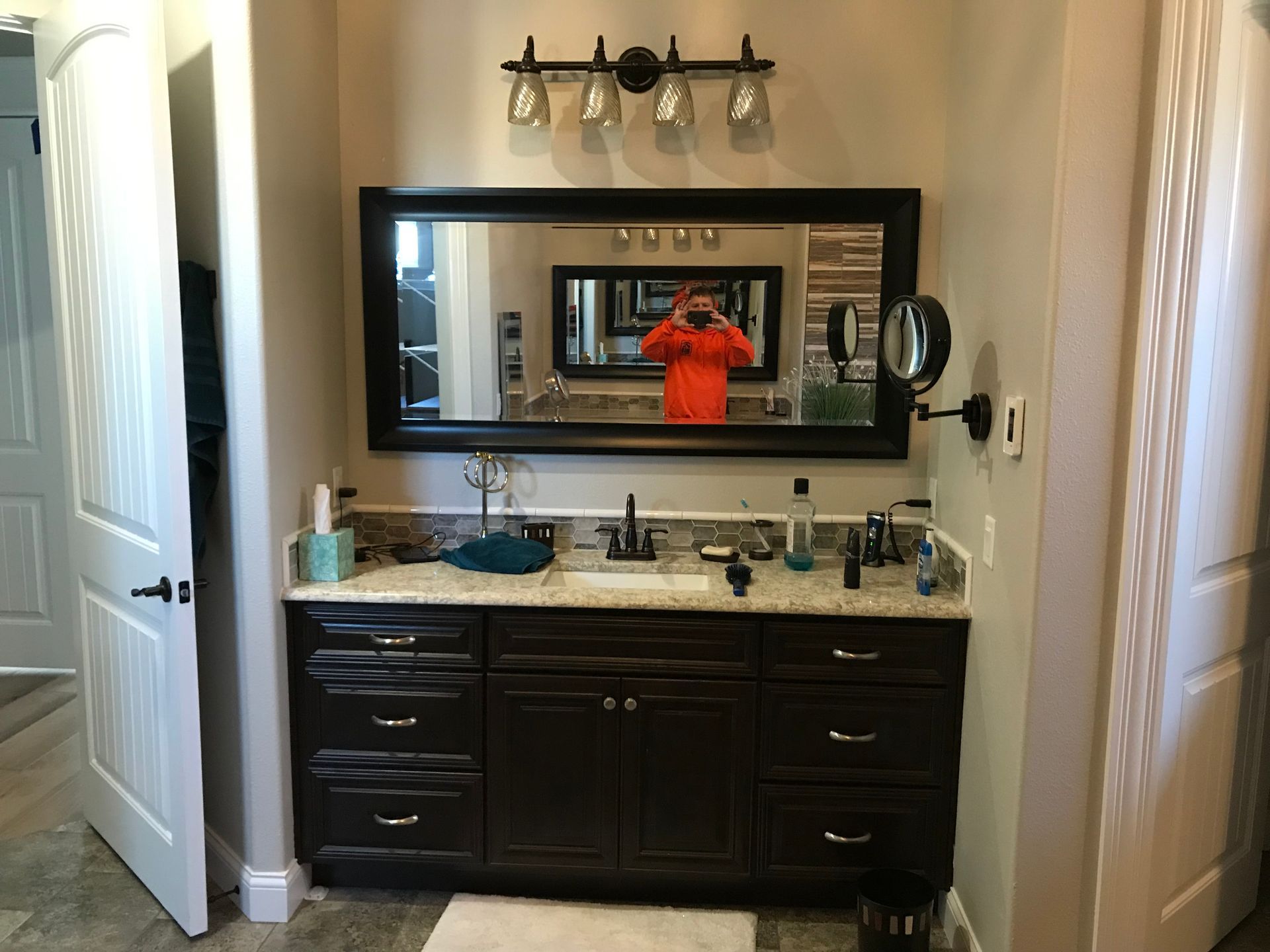 Bathroom vanity with dark cabinets, large mirror, and a person taking the photo reflected in the mirror