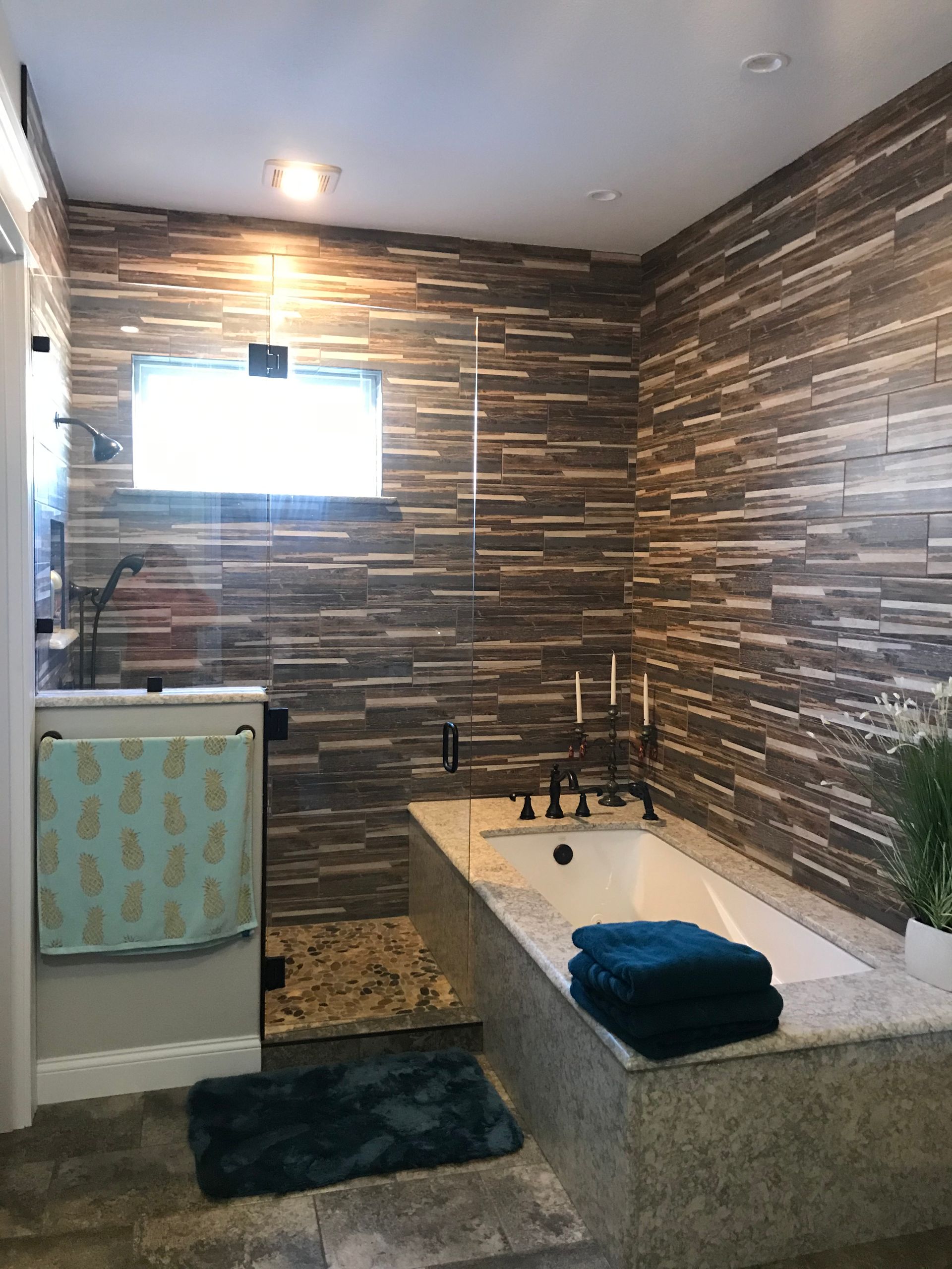 Modern bathroom with stone-pattern walls, soaking tub, towels, and a small window.