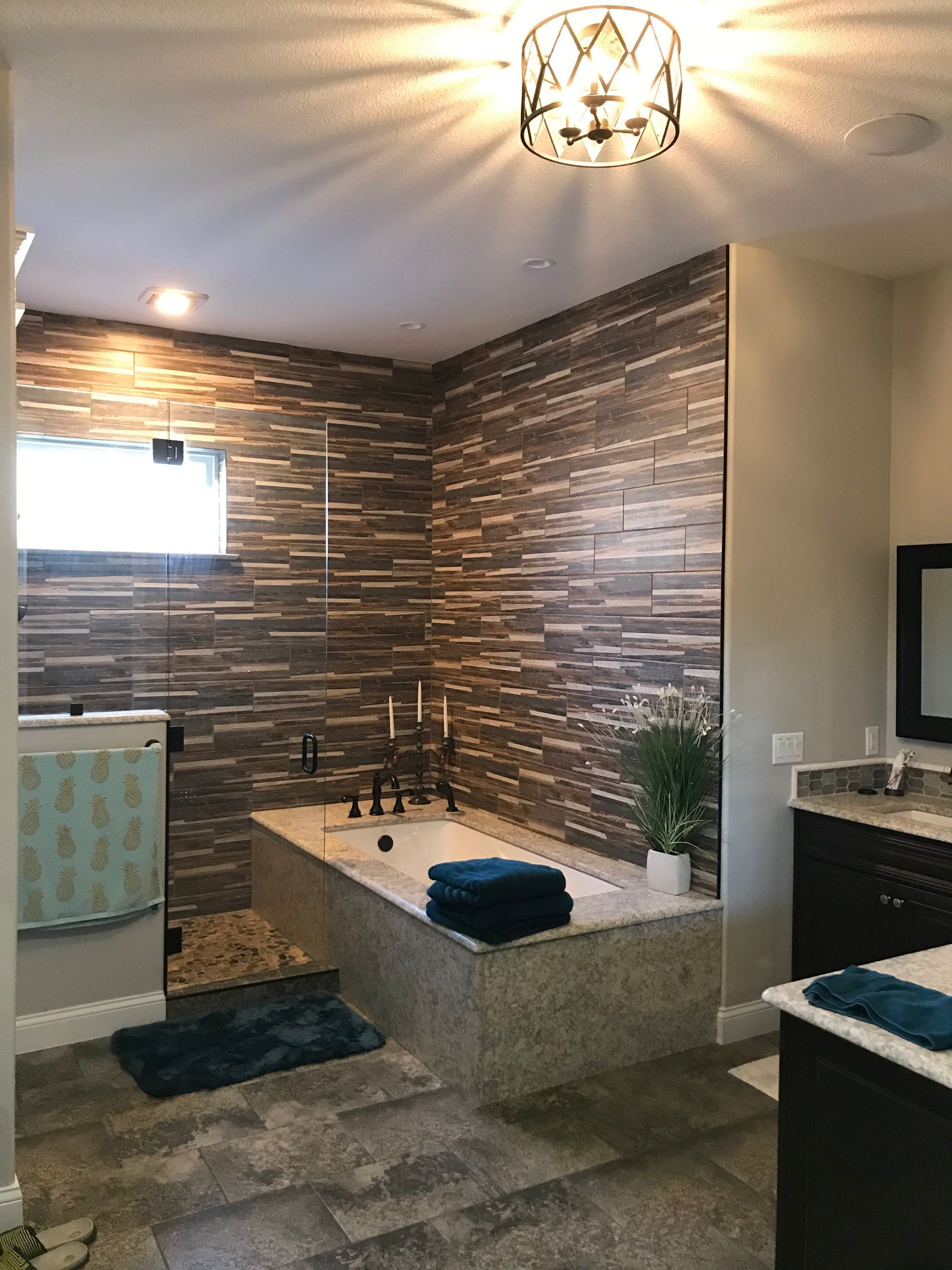 Modern bathroom with a soaking tub, tiled accent wall, window, and vanity sink.