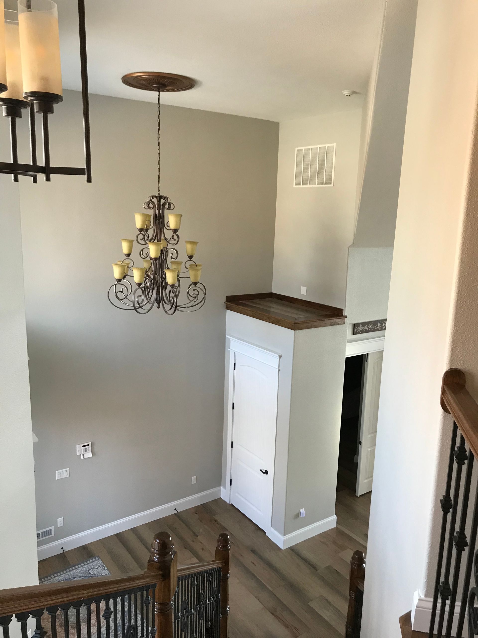 Staircase landing with chandelier, wall art, and a white cabinet in a bright home interior