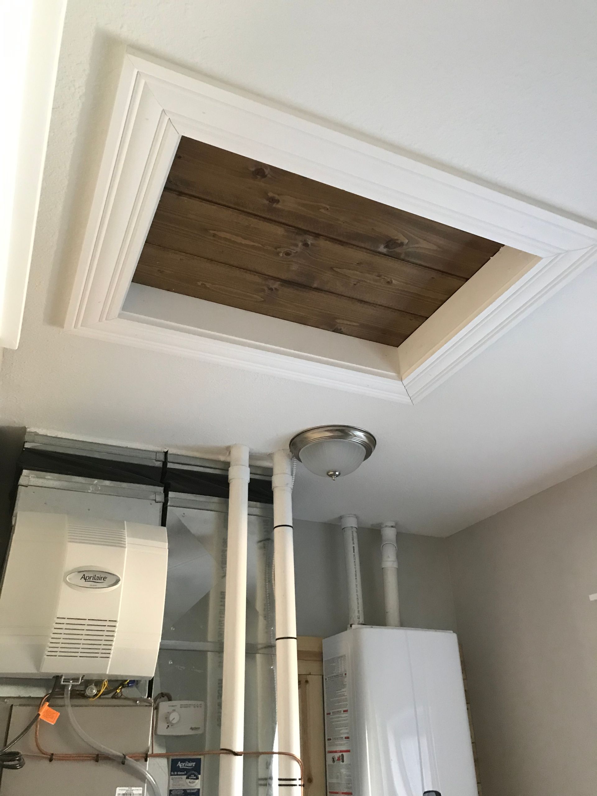 Open ceiling hatch with exposed attic space above utility equipment and pipes