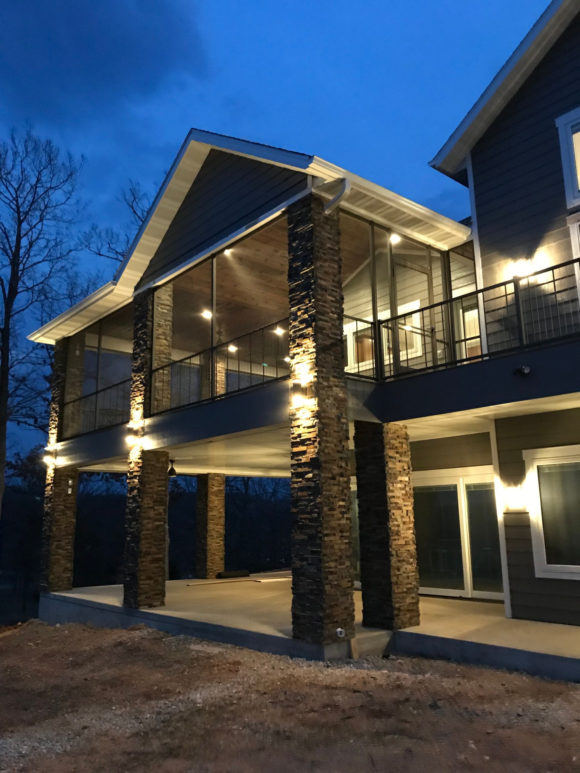 Lit modern two-story building with stone columns and large windows at dusk