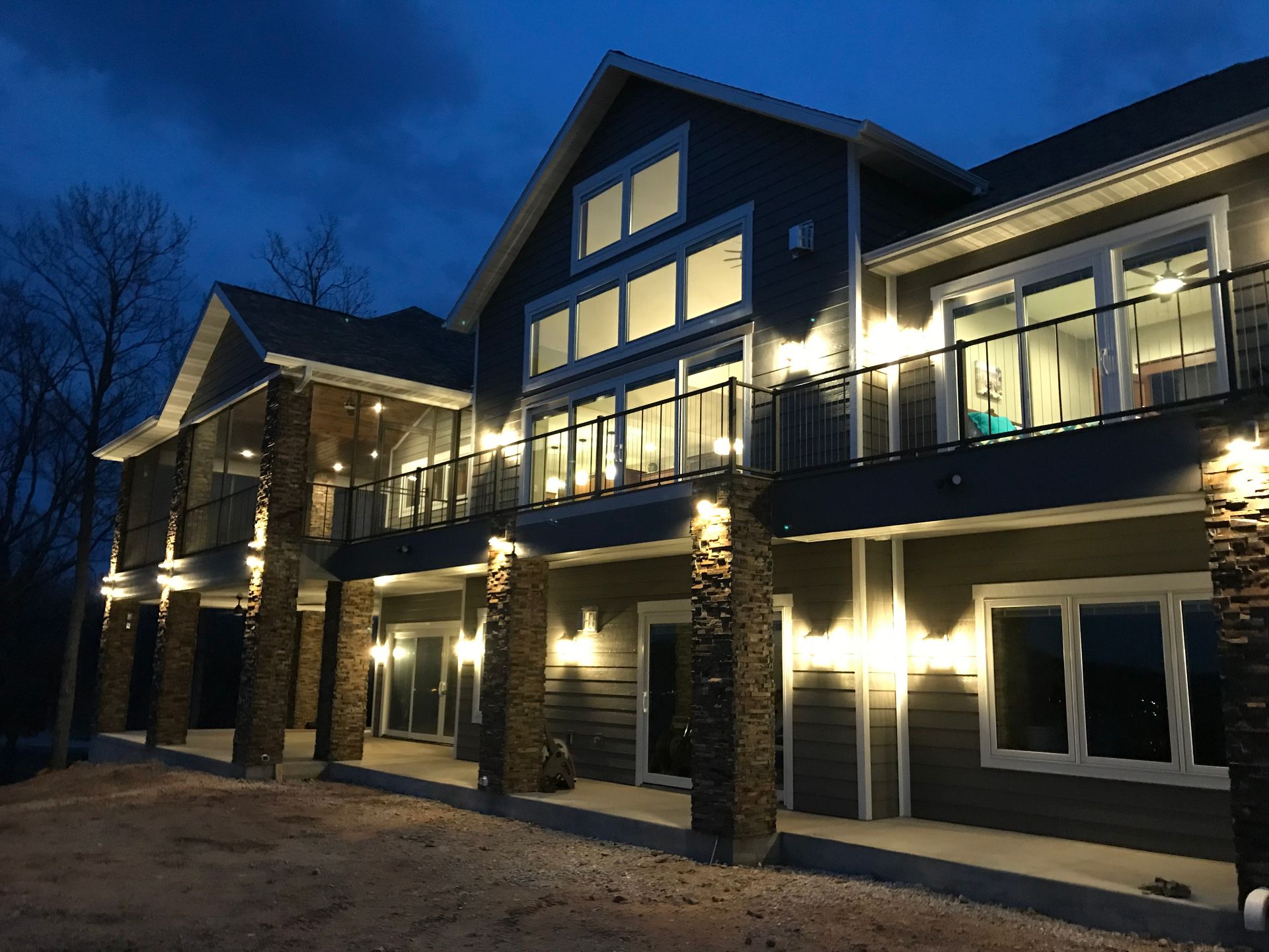 Illuminated modern townhouse exterior at dusk with balconies and stone columns