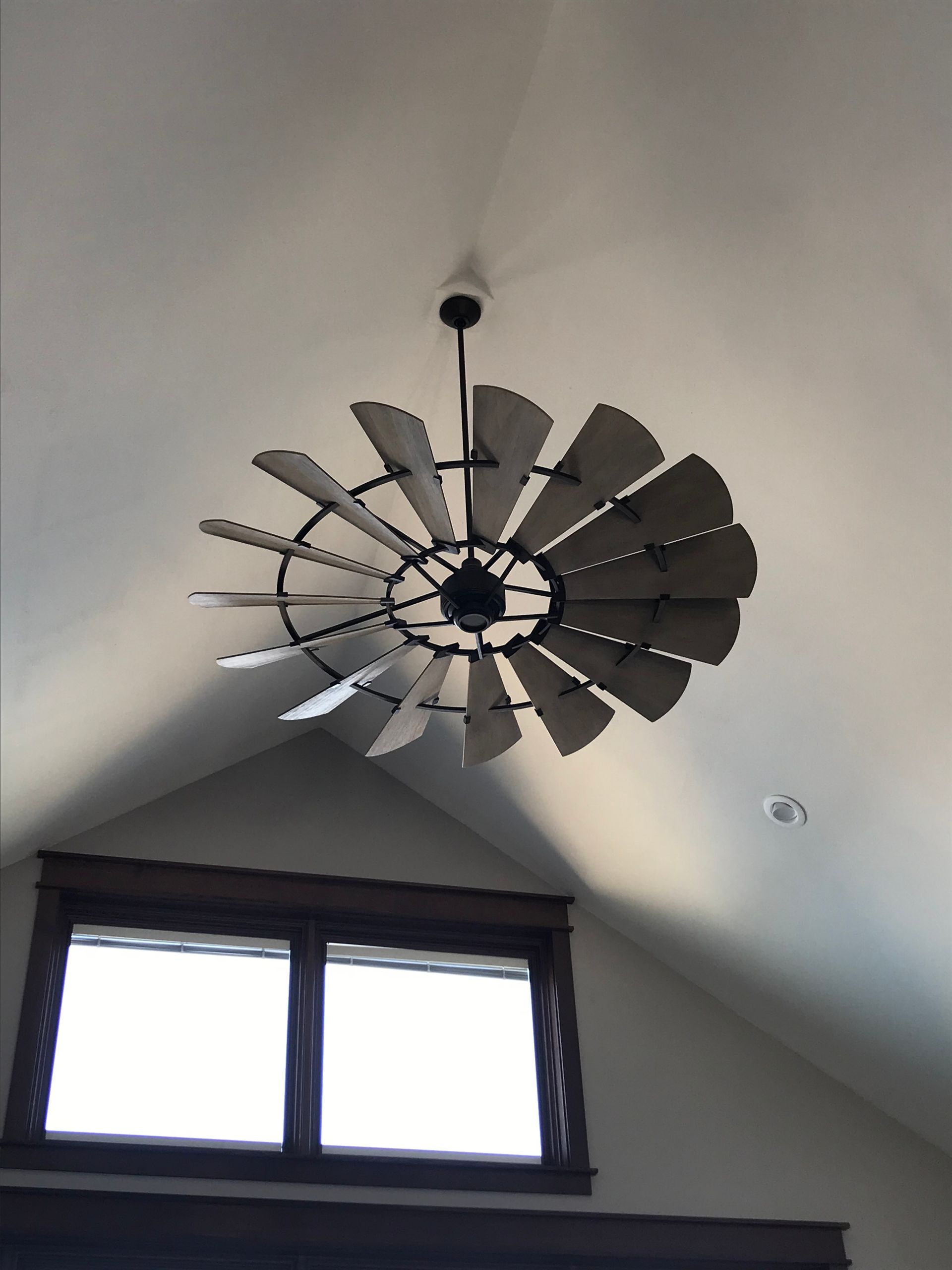 Decorative metal windmill-style ceiling fan above a small attic window