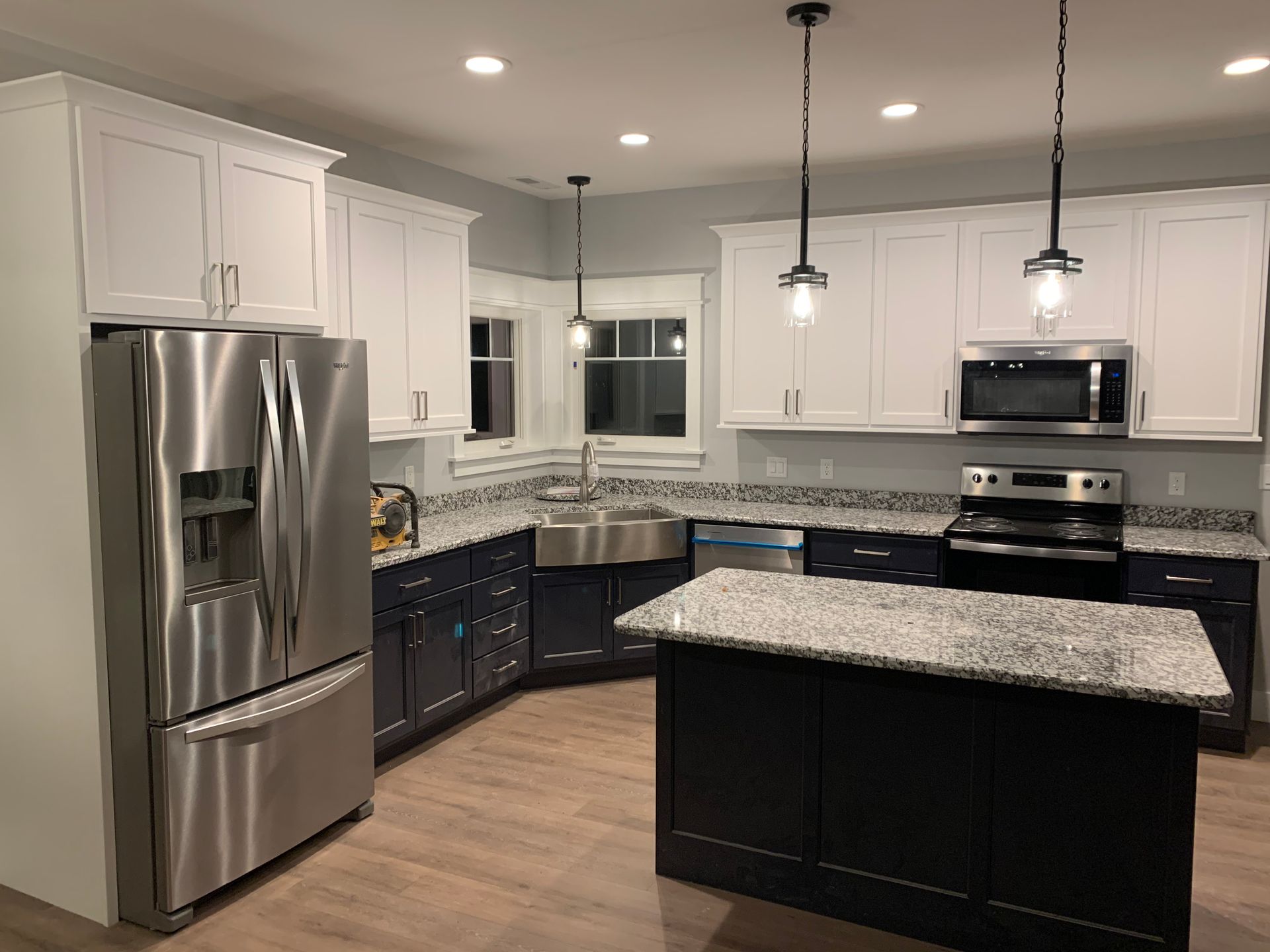 Modern kitchen with stainless steel appliances, white cabinets, dark island, and granite countertops