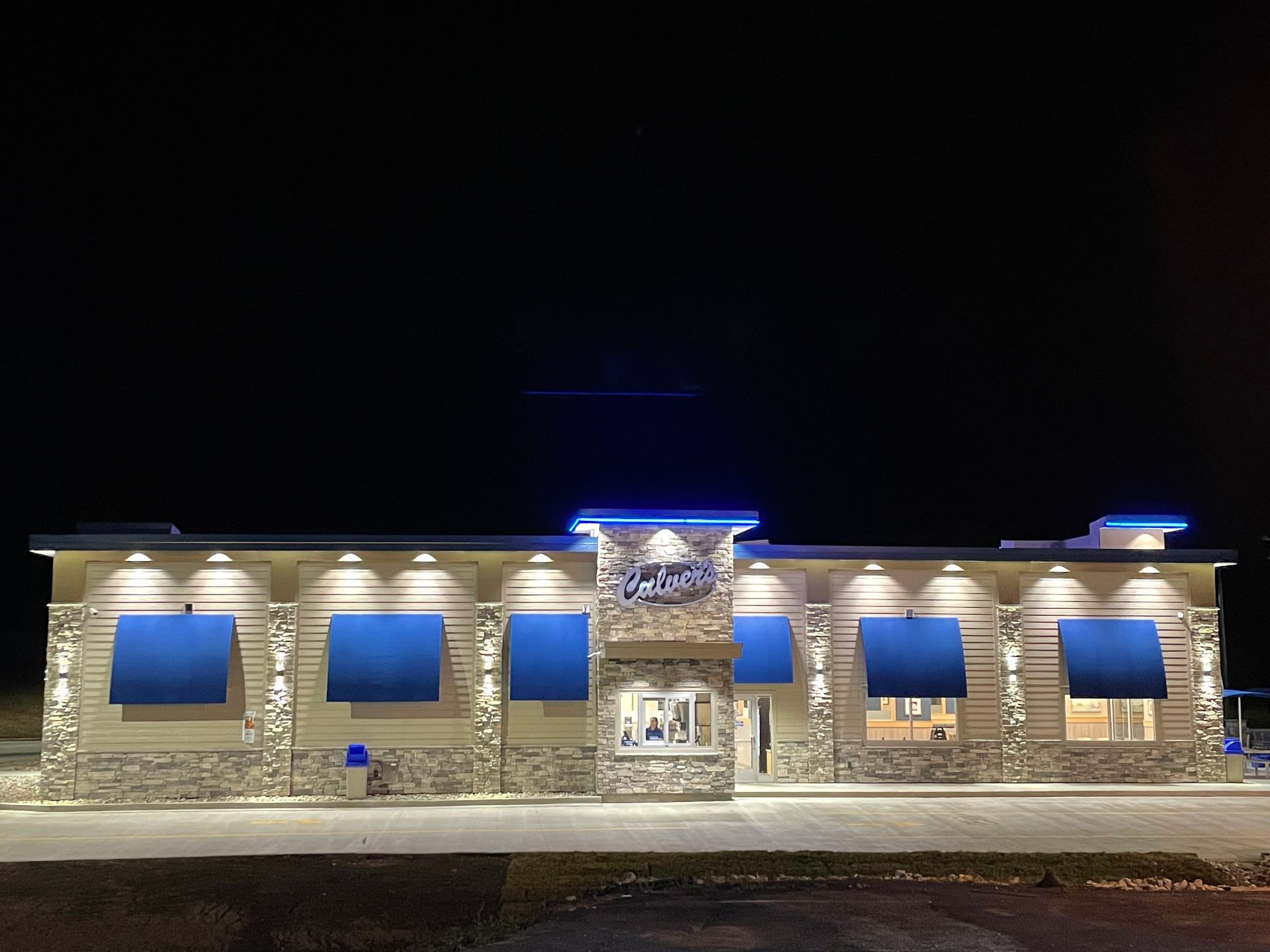 Well-lit stone building at night with blue-lit windows and central entrance