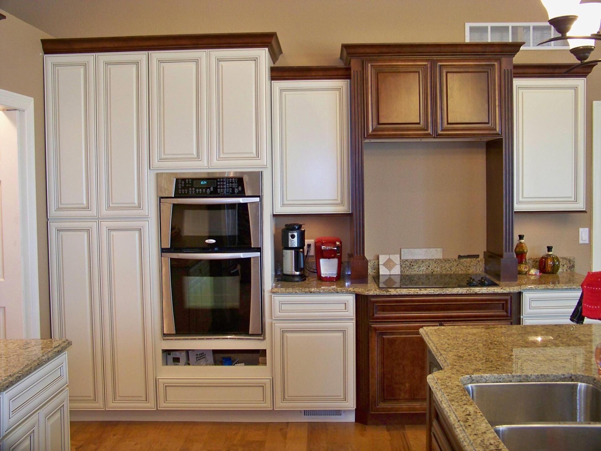 Kitchen with white cabinets, double ovens, wooden island, and granite countertops