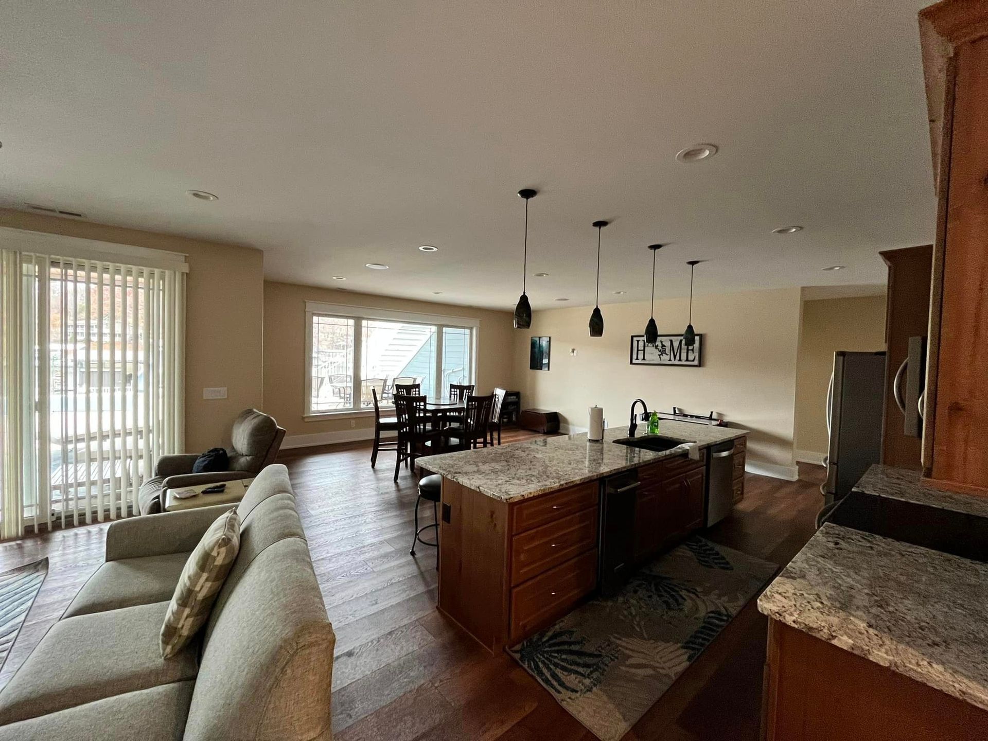 Open-plan living room and kitchen with beige sofa, dining table, island, and hardwood floors
