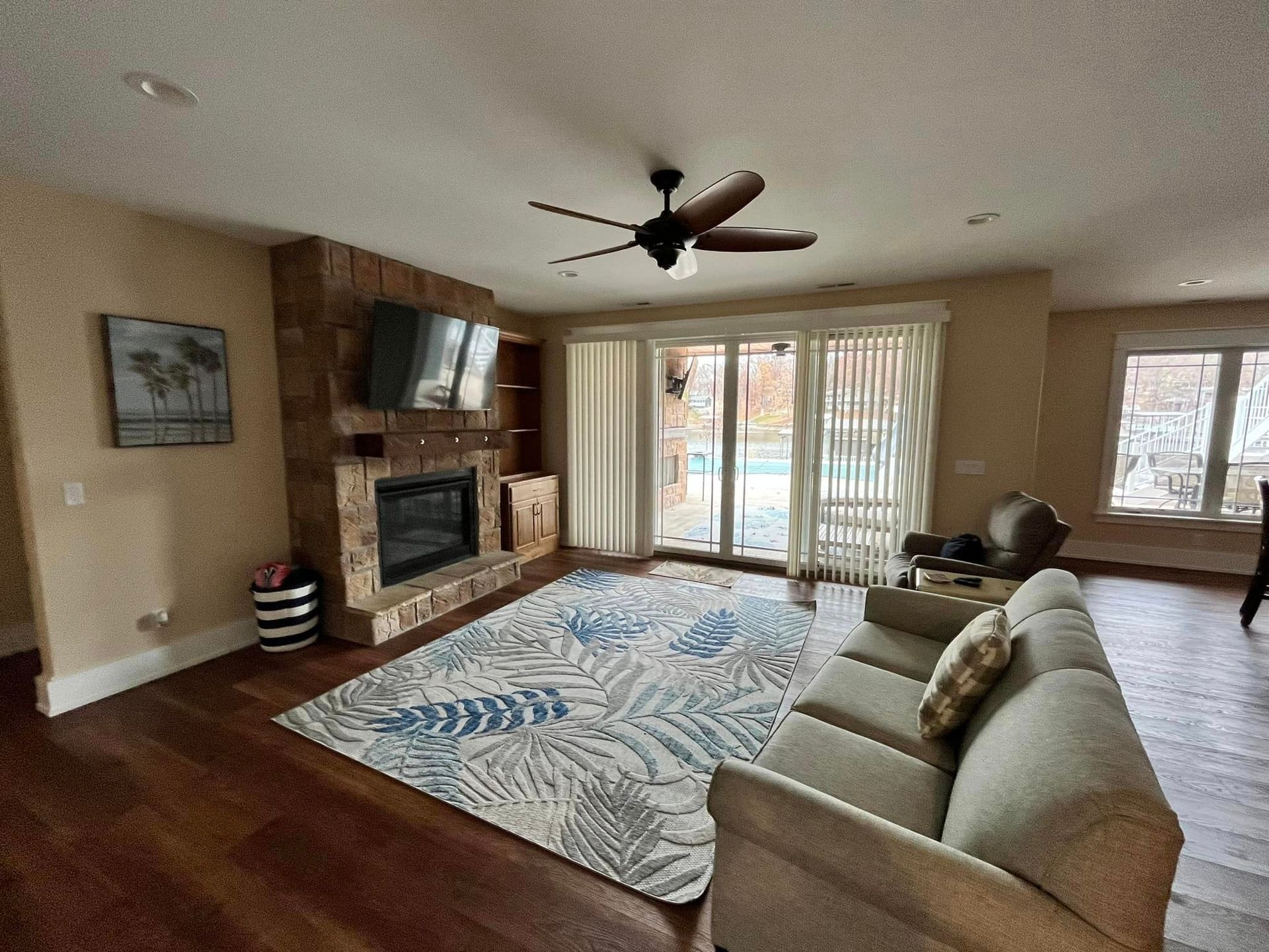 Living room with sectional sofa, fireplace, TV, patterned rug, and sliding glass doors to a deck