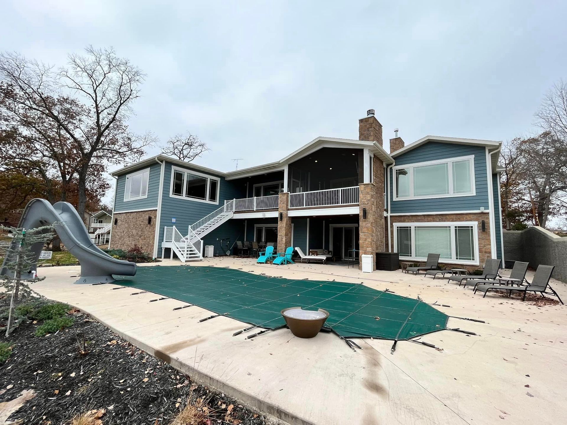Backyard patio with a house, pool slide, and green turf area under construction