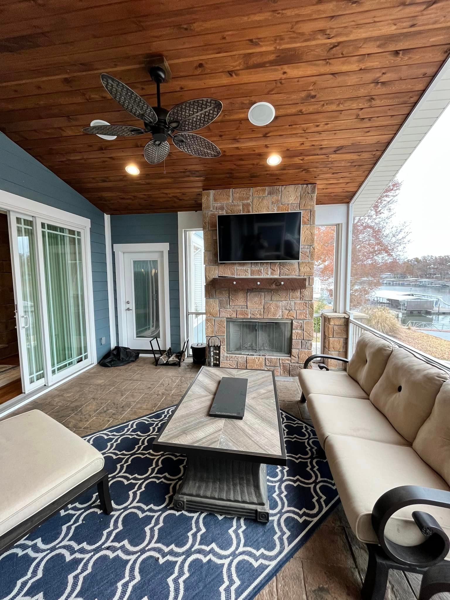 Covered patio with sofa, coffee table, fireplace, TV, and ceiling fan overlooking snowy outdoors
