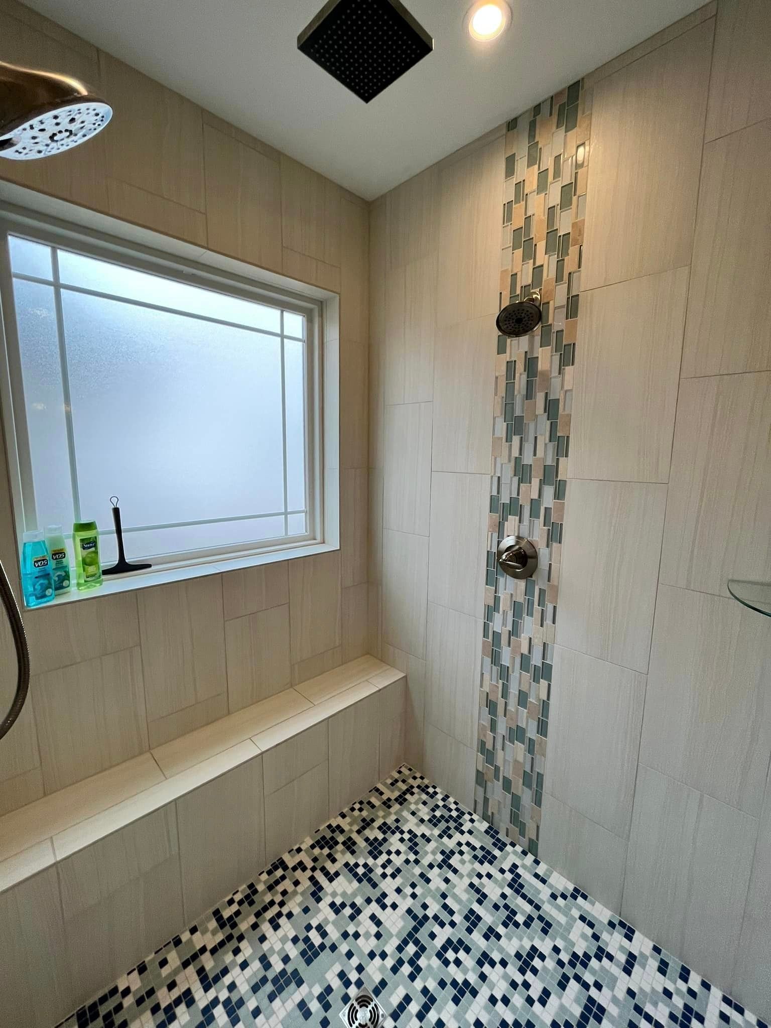 Small bathroom with a window, bench seat, and black-and-white mosaic tile floor and accent wall.