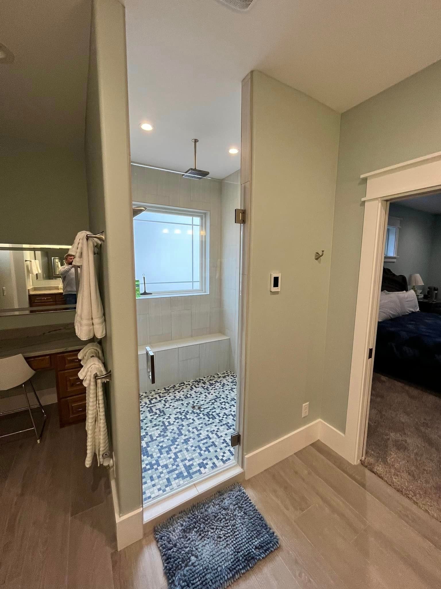 Hallway view into a bathroom with patterned floor, beige walls, and a blue rug at the doorway.