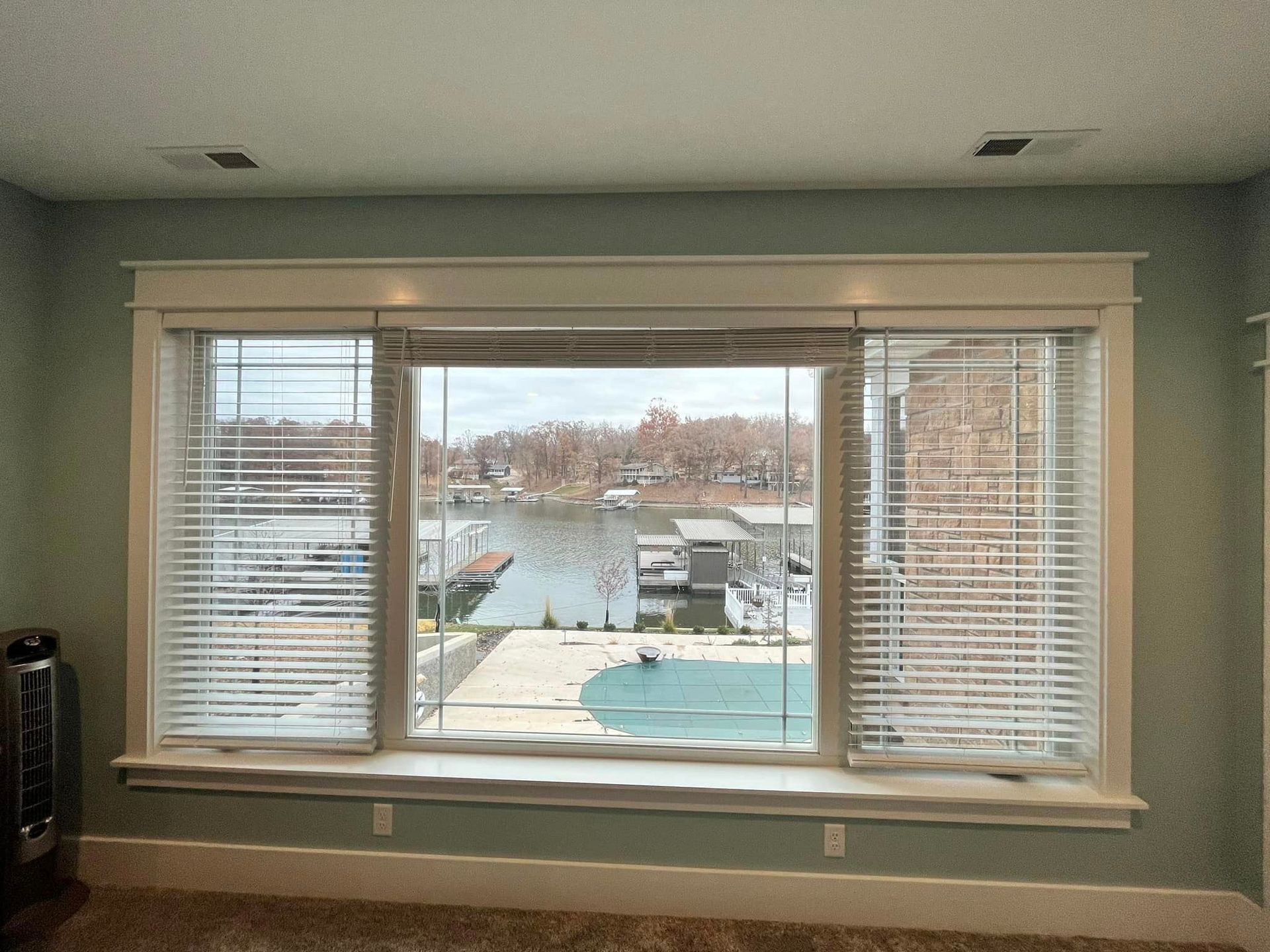Living room window with blinds overlooking a waterfront dock and boats