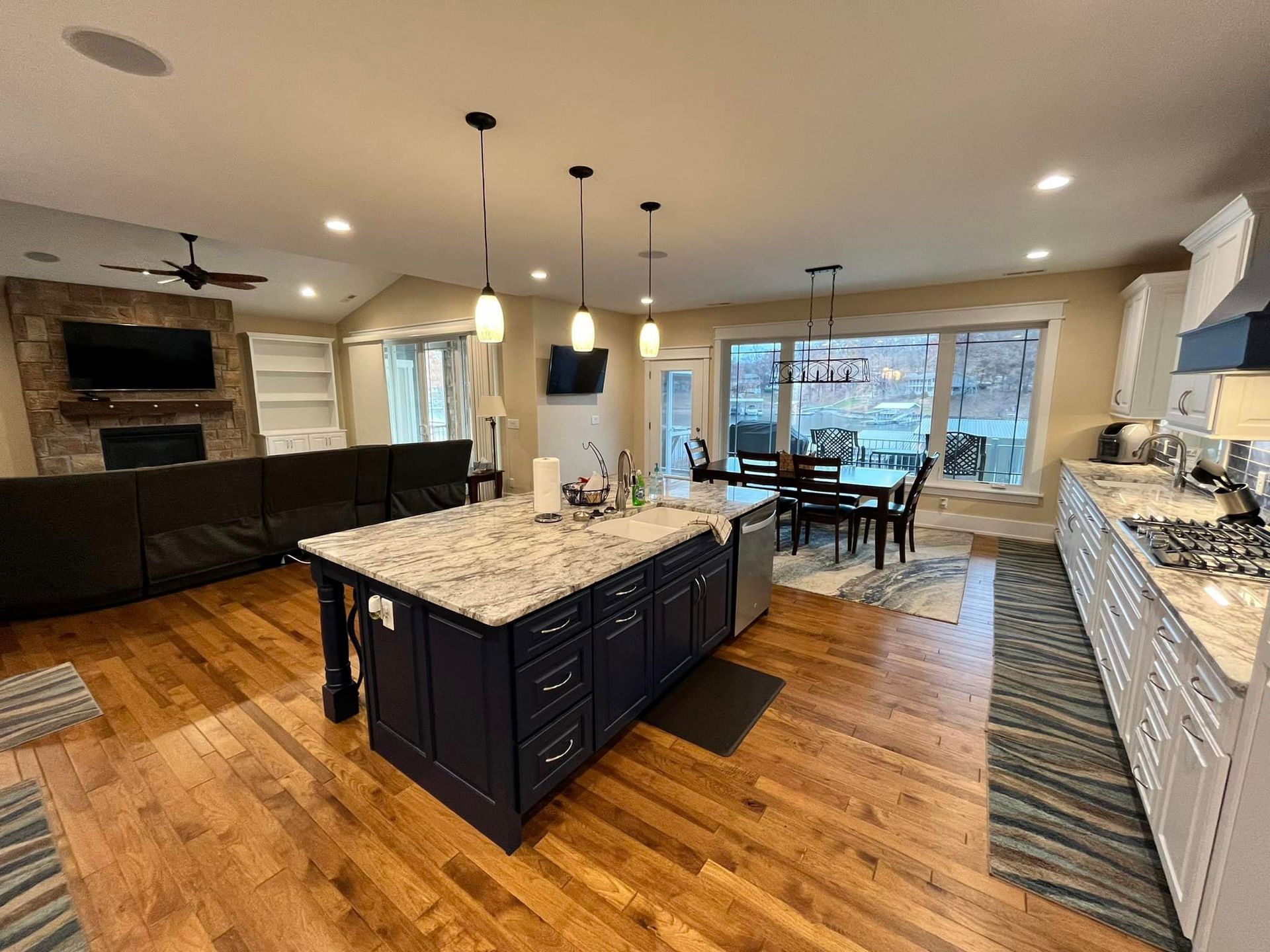 Modern kitchen with granite island, hardwood floors, pendant lights, and dining area by large windows