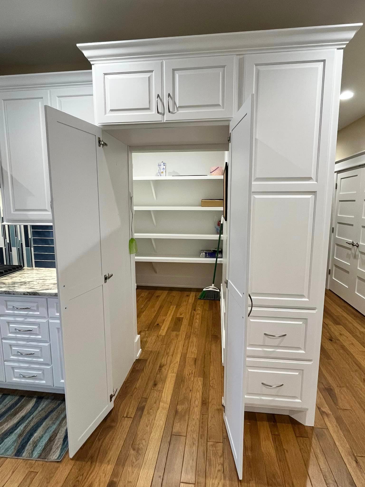 White built-in closet with open double doors, shelves inside, and drawers on the right in a bedroom.