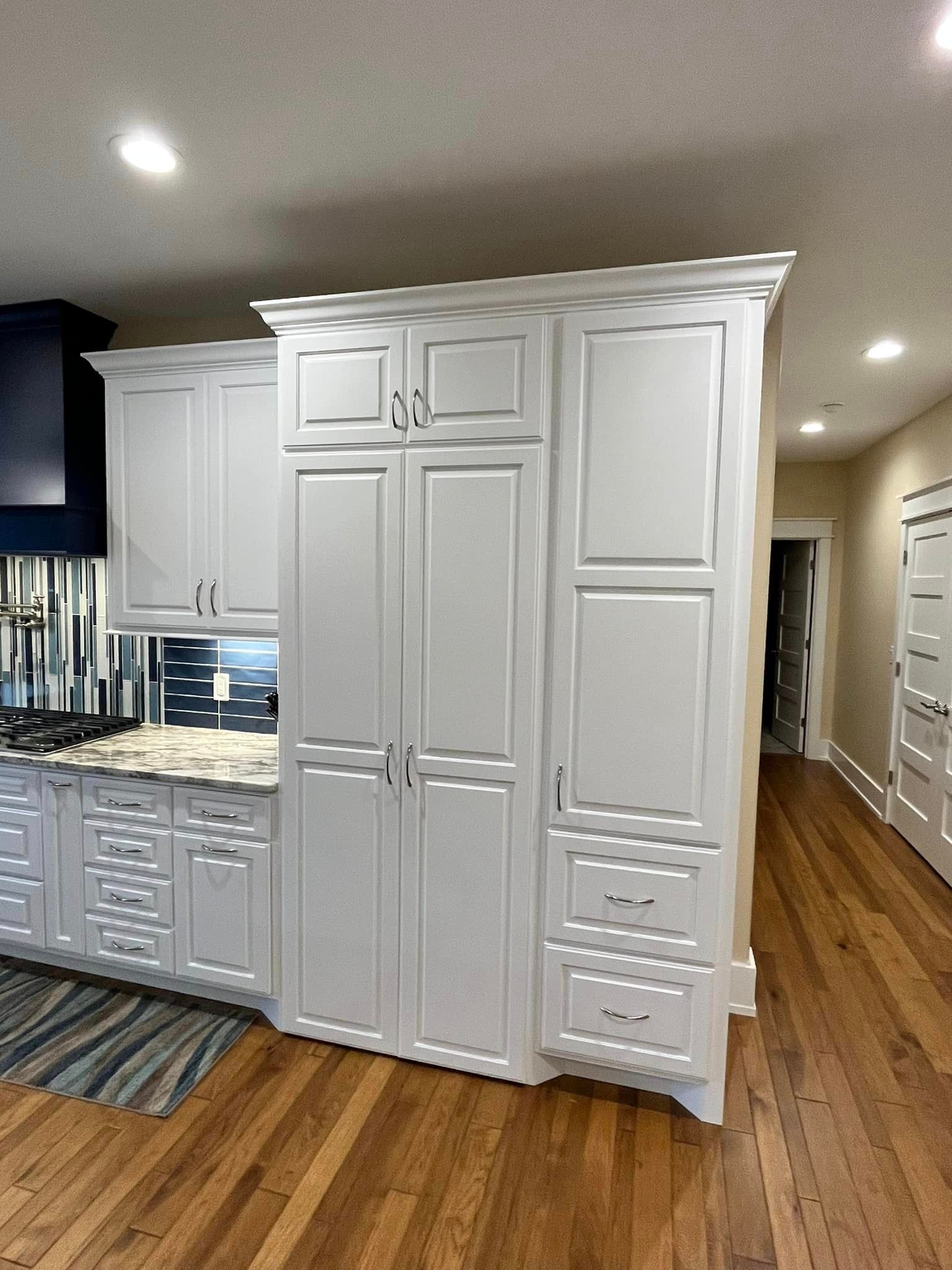 White kitchen cabinets with built-in refrigerator and granite countertop in a home interior