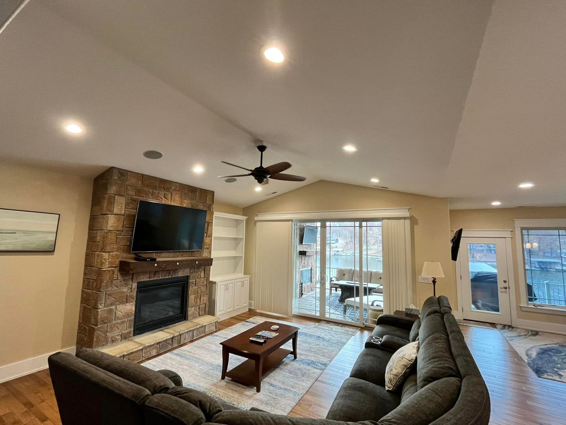 Spacious living room with sectional sofa, stone fireplace, TV, coffee table, and sliding glass doors.