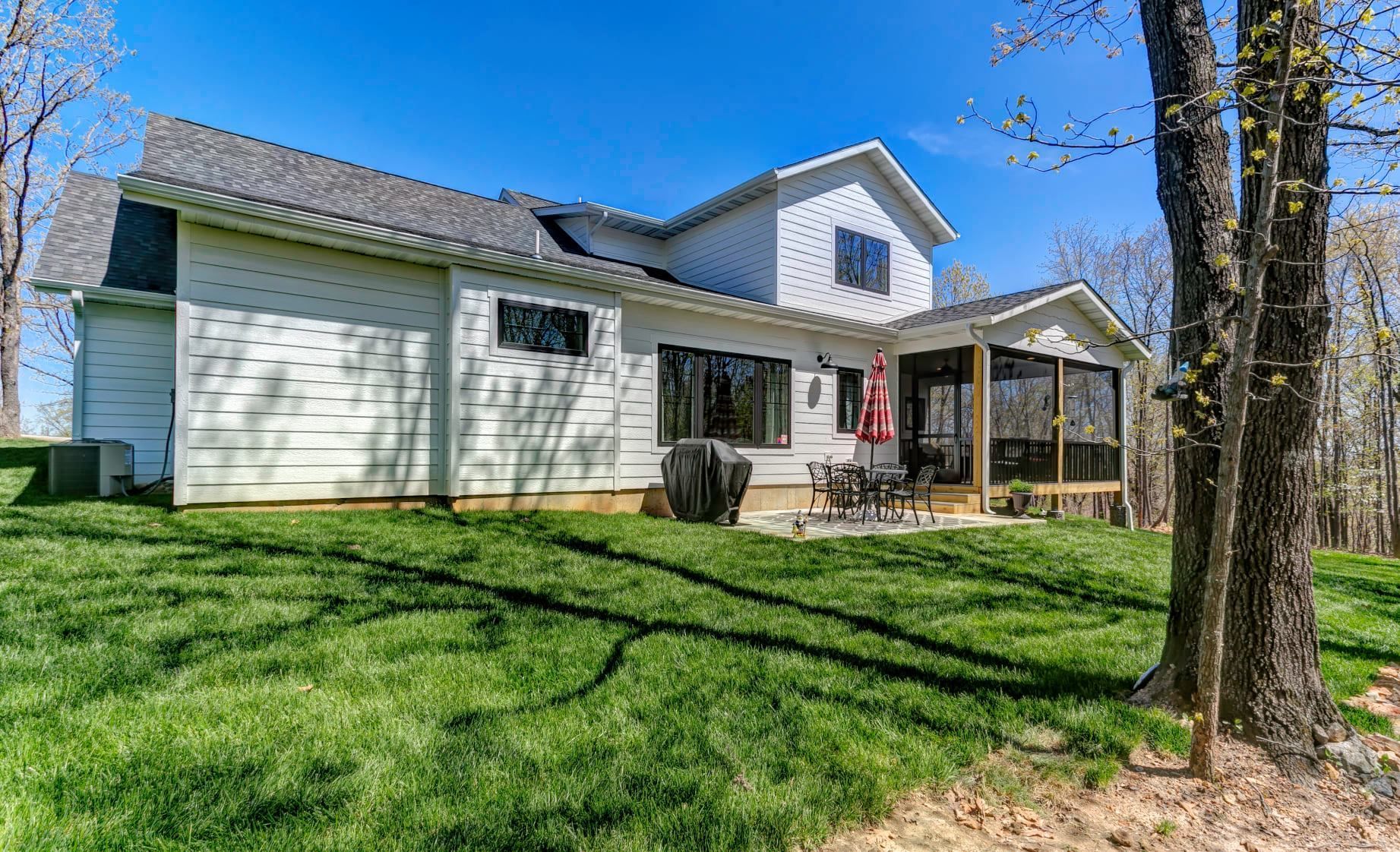White house with screened porch and green lawn under a clear blue sky