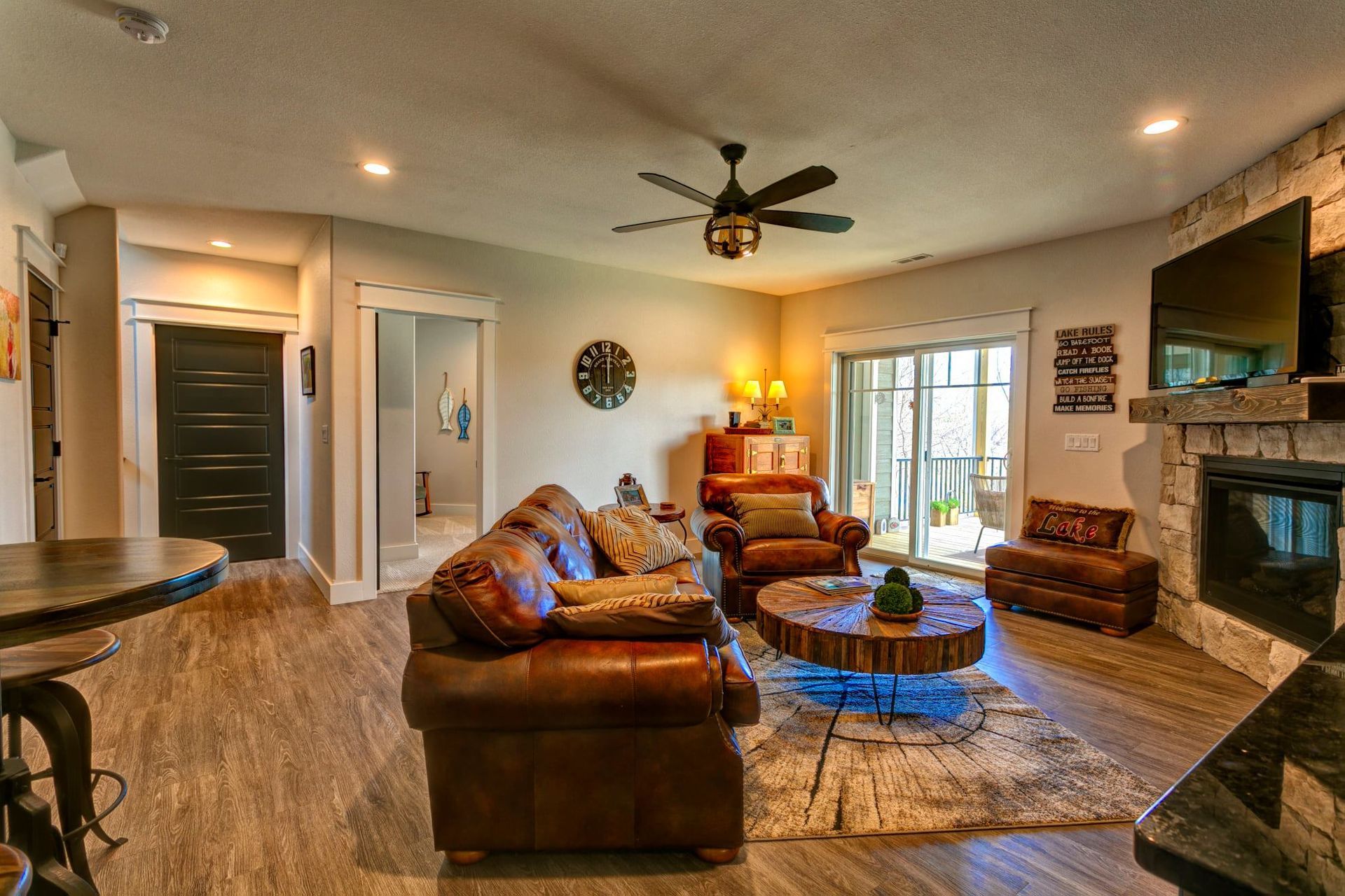 Cozy living room with leather sofas, fireplace, wall TV, and warm lighting