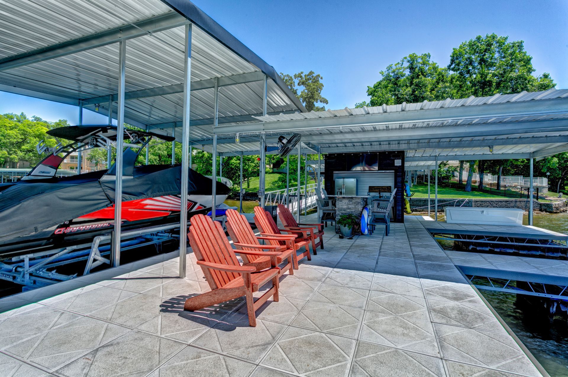 Covered marina seating area with orange chairs beside boats and calm water