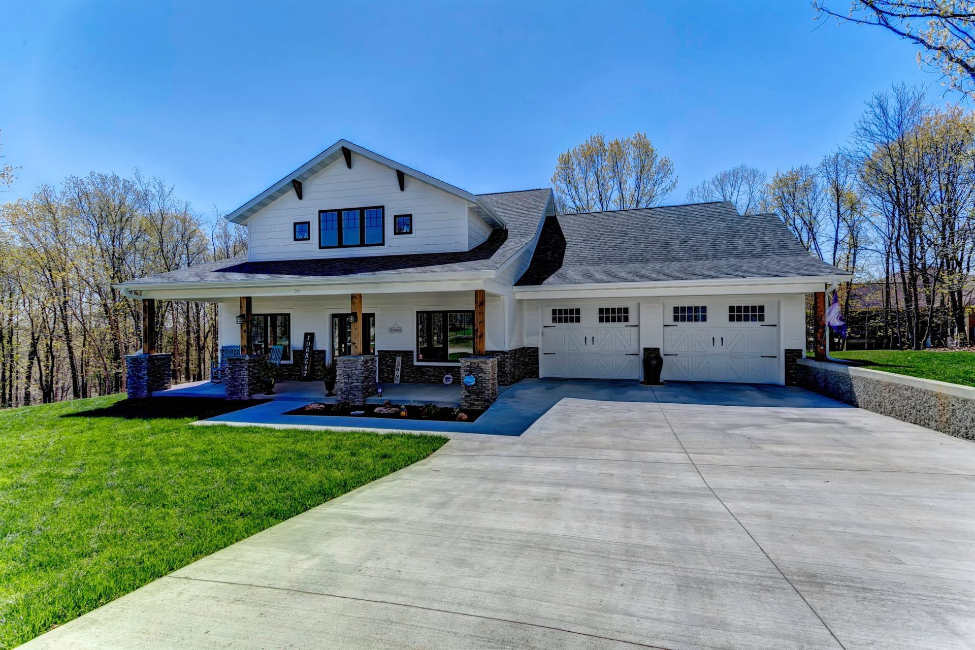 Modern two-story house with a wide driveway, front porch, and attached garage on a sunny day