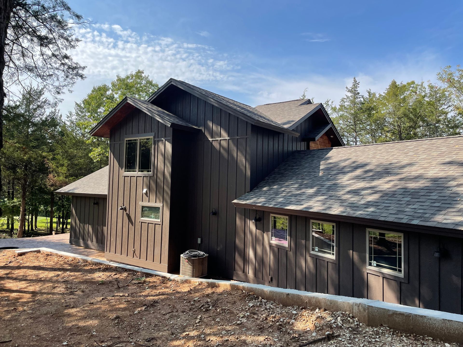 Weathered dark wooden cabin buildings among trees under a blue sky