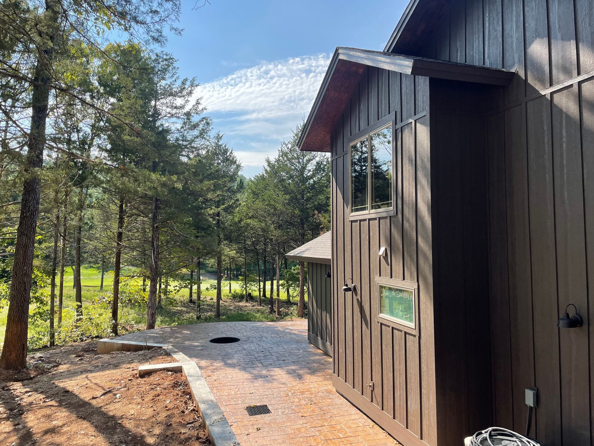 Wooden cabin beside a gravel path in a sunny pine forest
