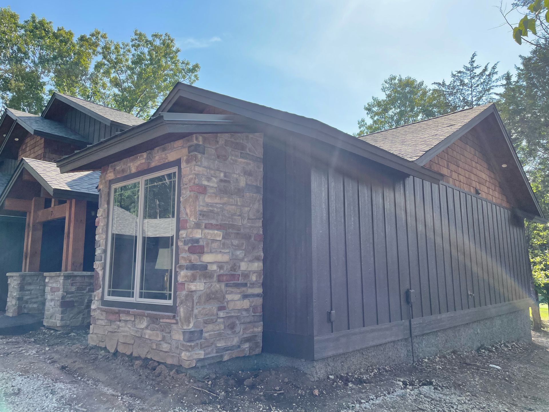 Stone and wood house exterior with a covered side porch under a blue sky
