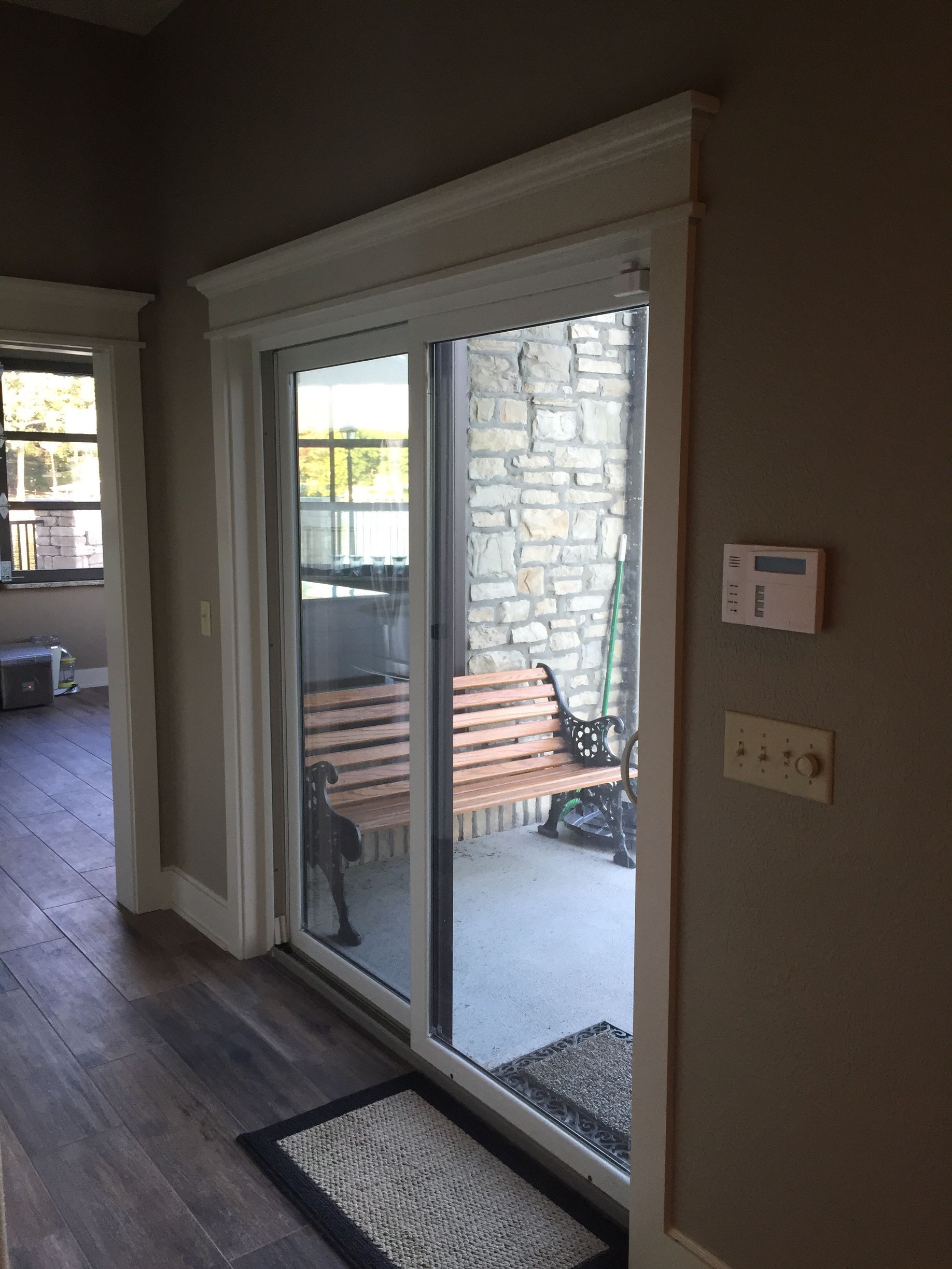 Indoor view of sliding glass patio doors opening to a stone-walled patio with bench and steps