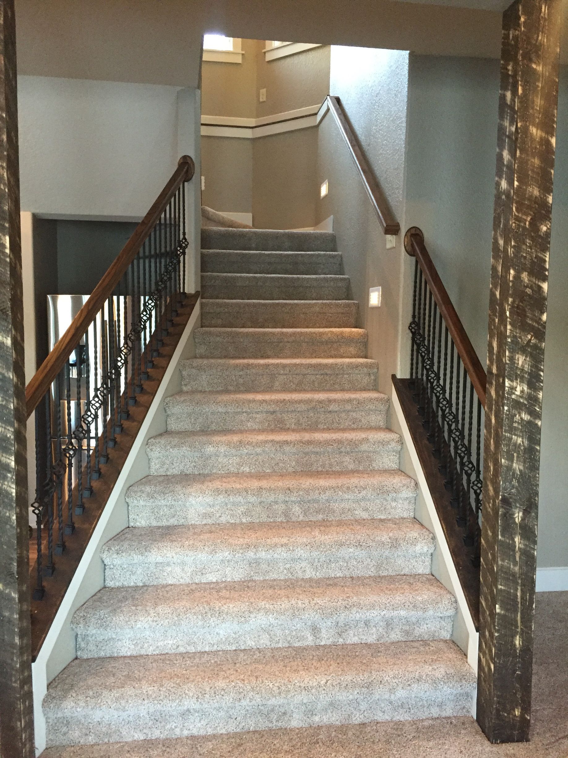 Carpeted indoor staircase with wooden railings leading to an upper landing.