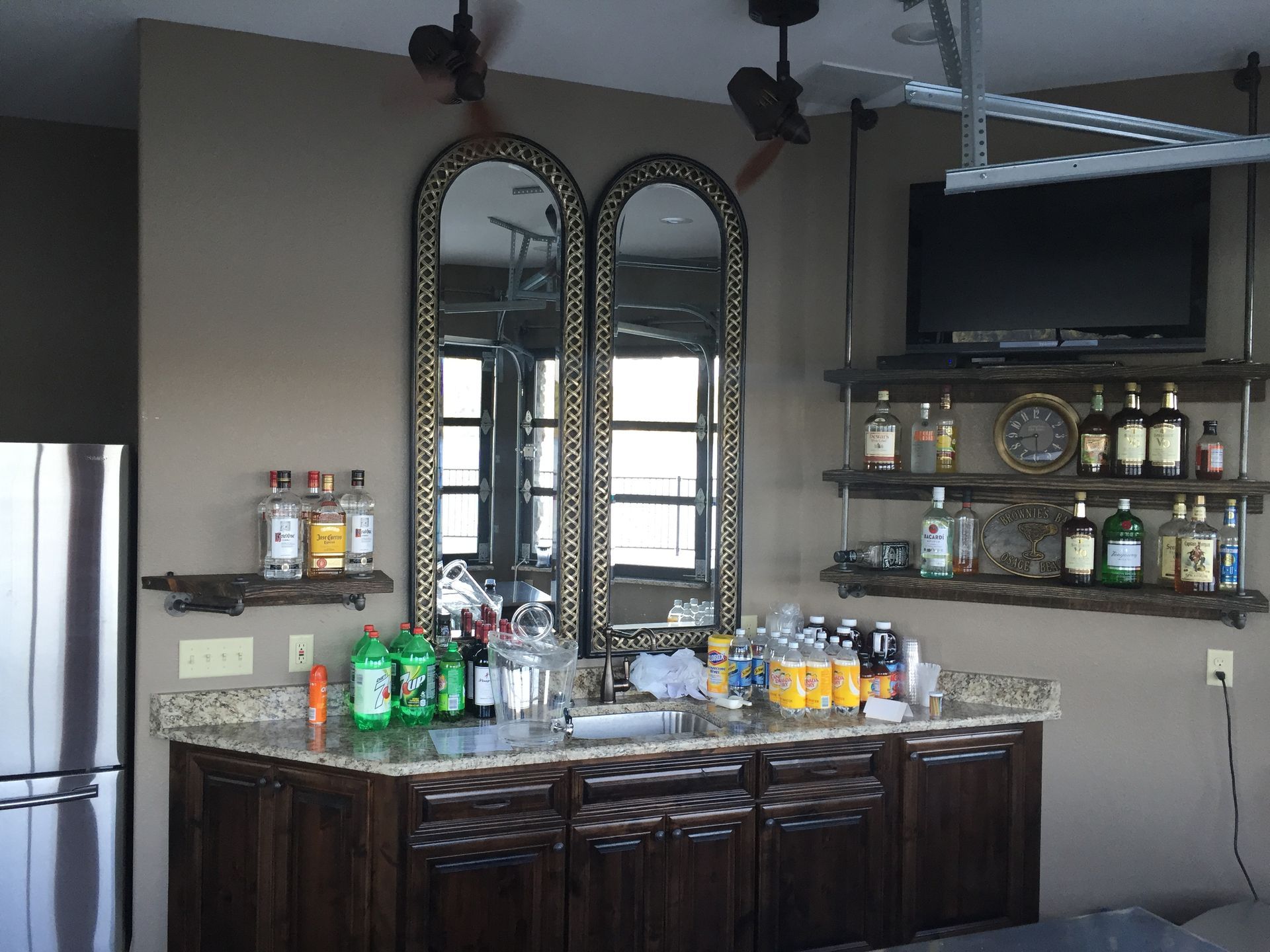 Modern home bar with mirrored cabinets, bottles, glassware, and a stainless refrigerator