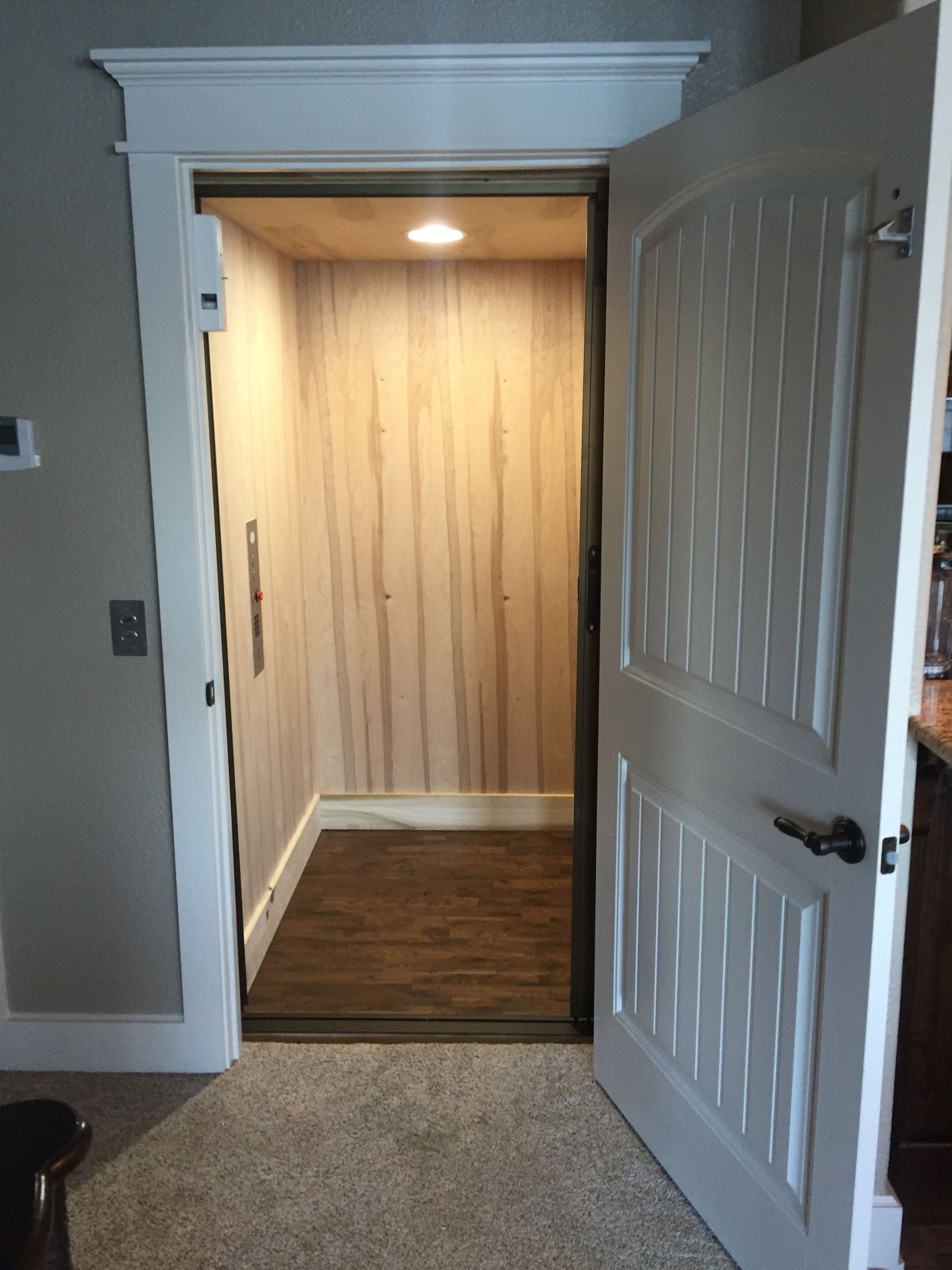 Open doorway to a narrow, wood-paneled room with dark hardwood floor and a ceiling light on.
