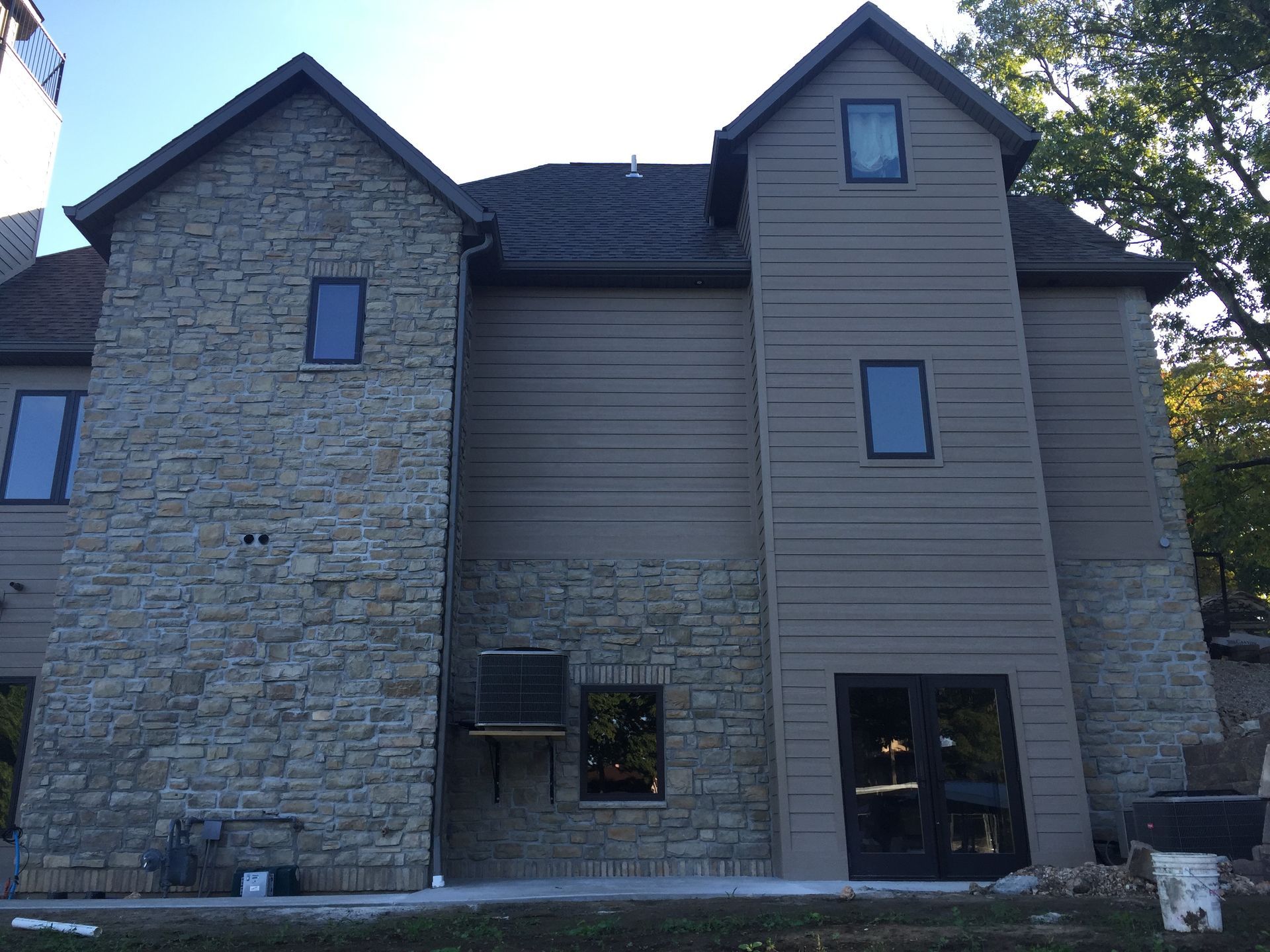 Stone-and-siding apartment building exterior with windows and a small ground-level entrance