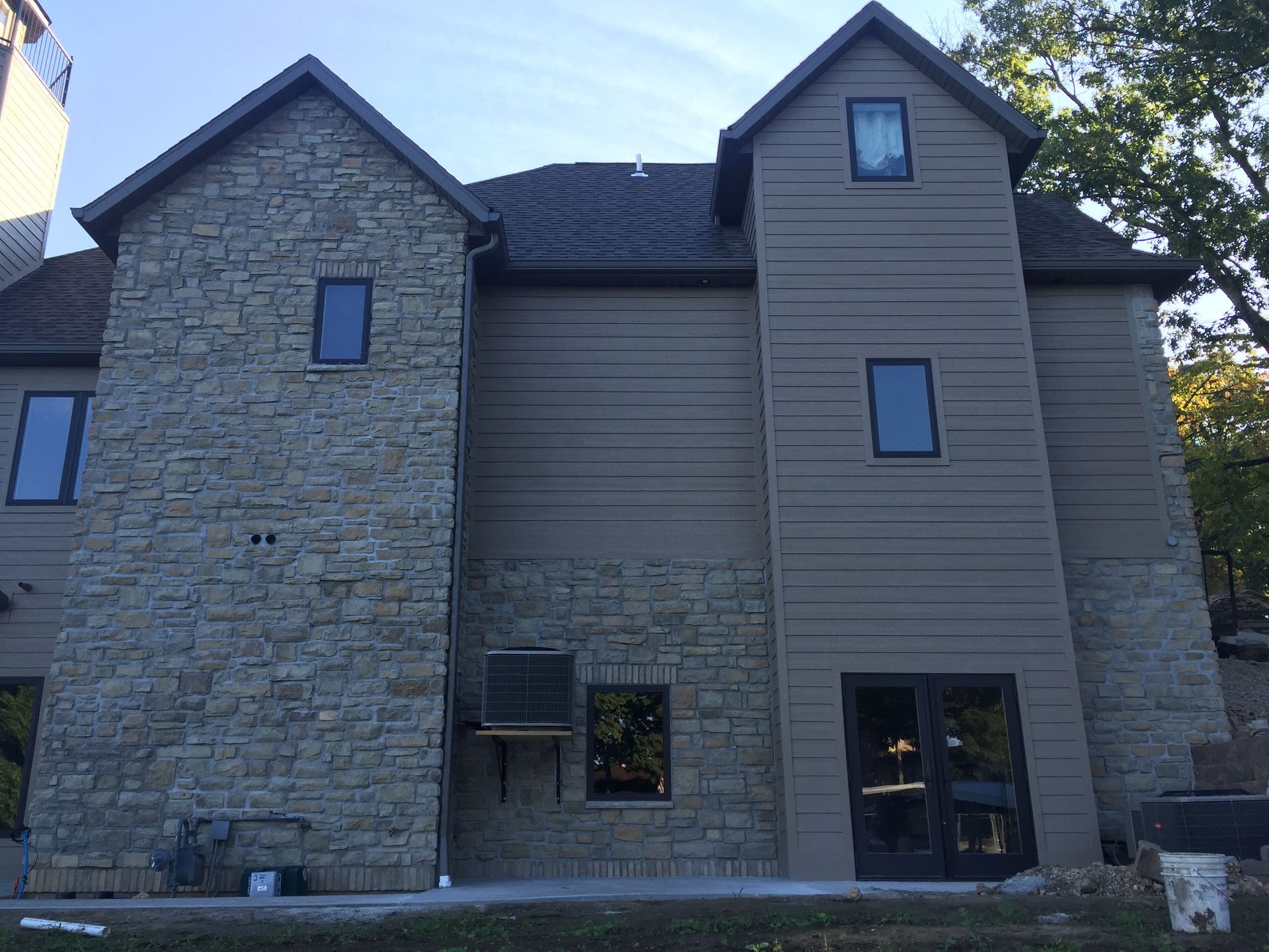 Stone and tan-sided apartment building exterior with windows and a glass door