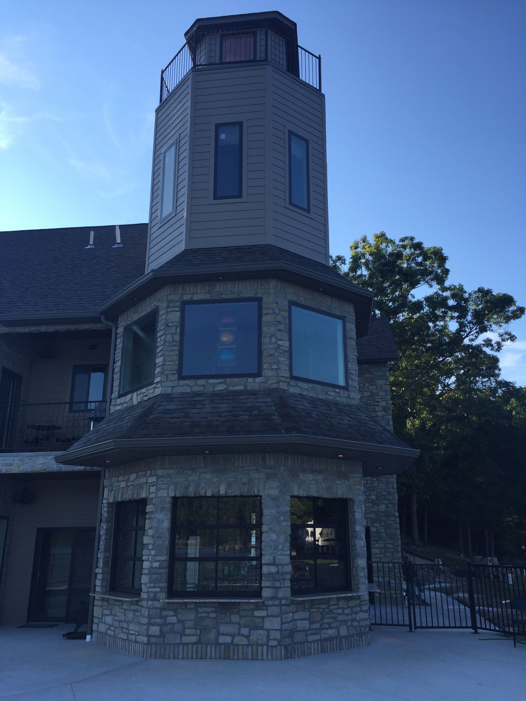 Stone turret on a house with large windows and a blue sky in the background