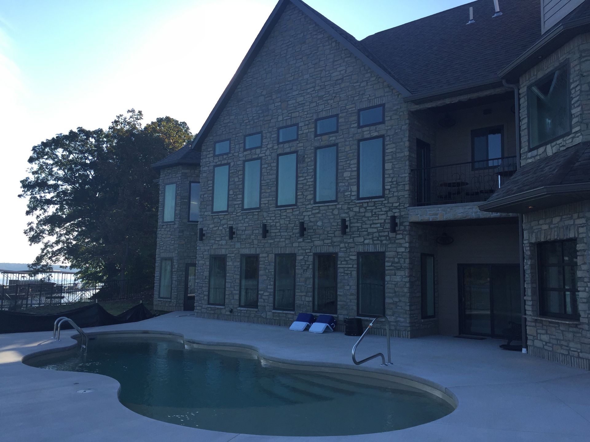 Stone house patio with an empty swimming pool at dusk