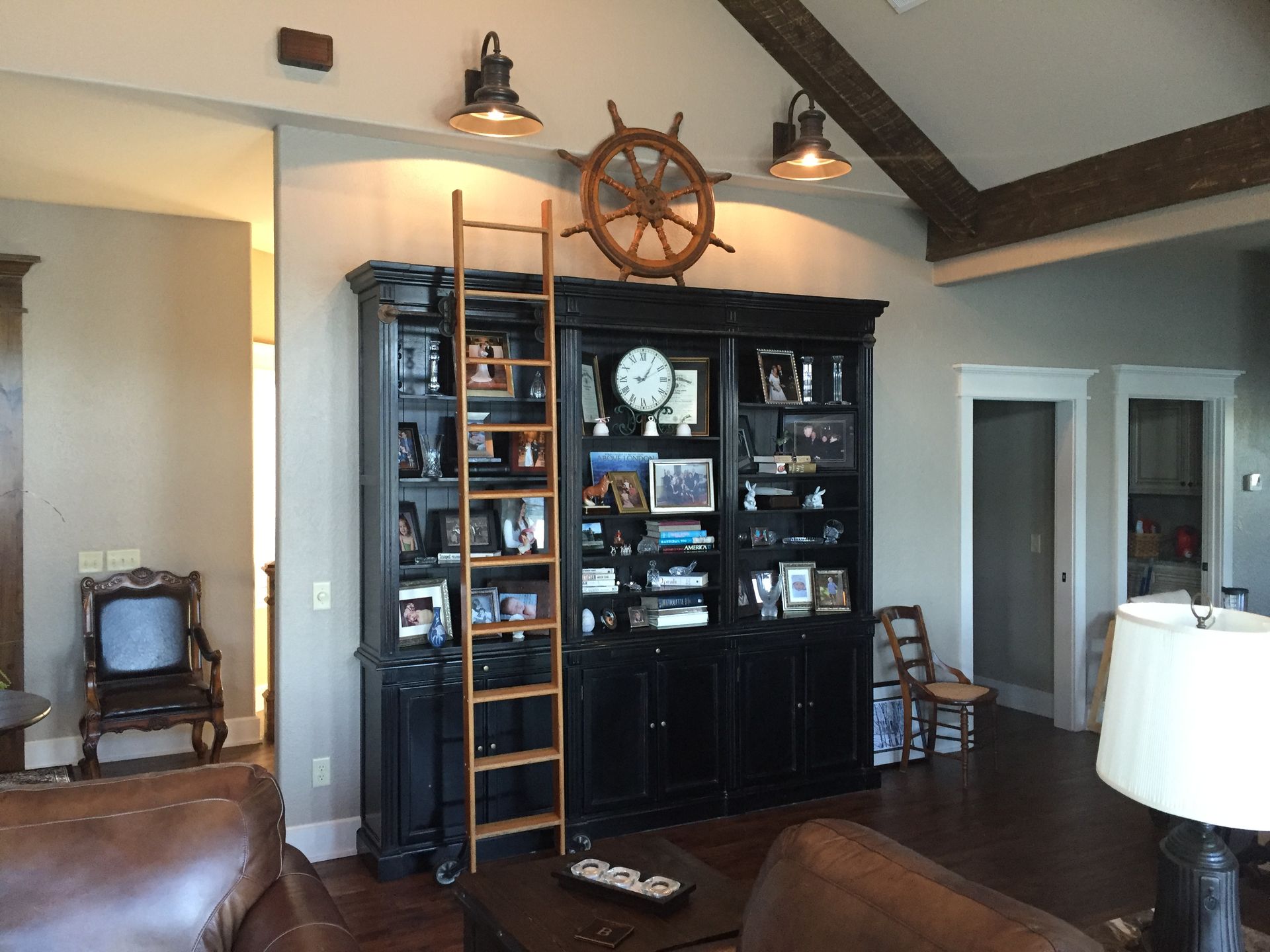 Living room with a black entertainment cabinet, ladder, nautical decor, and high vaulted ceiling