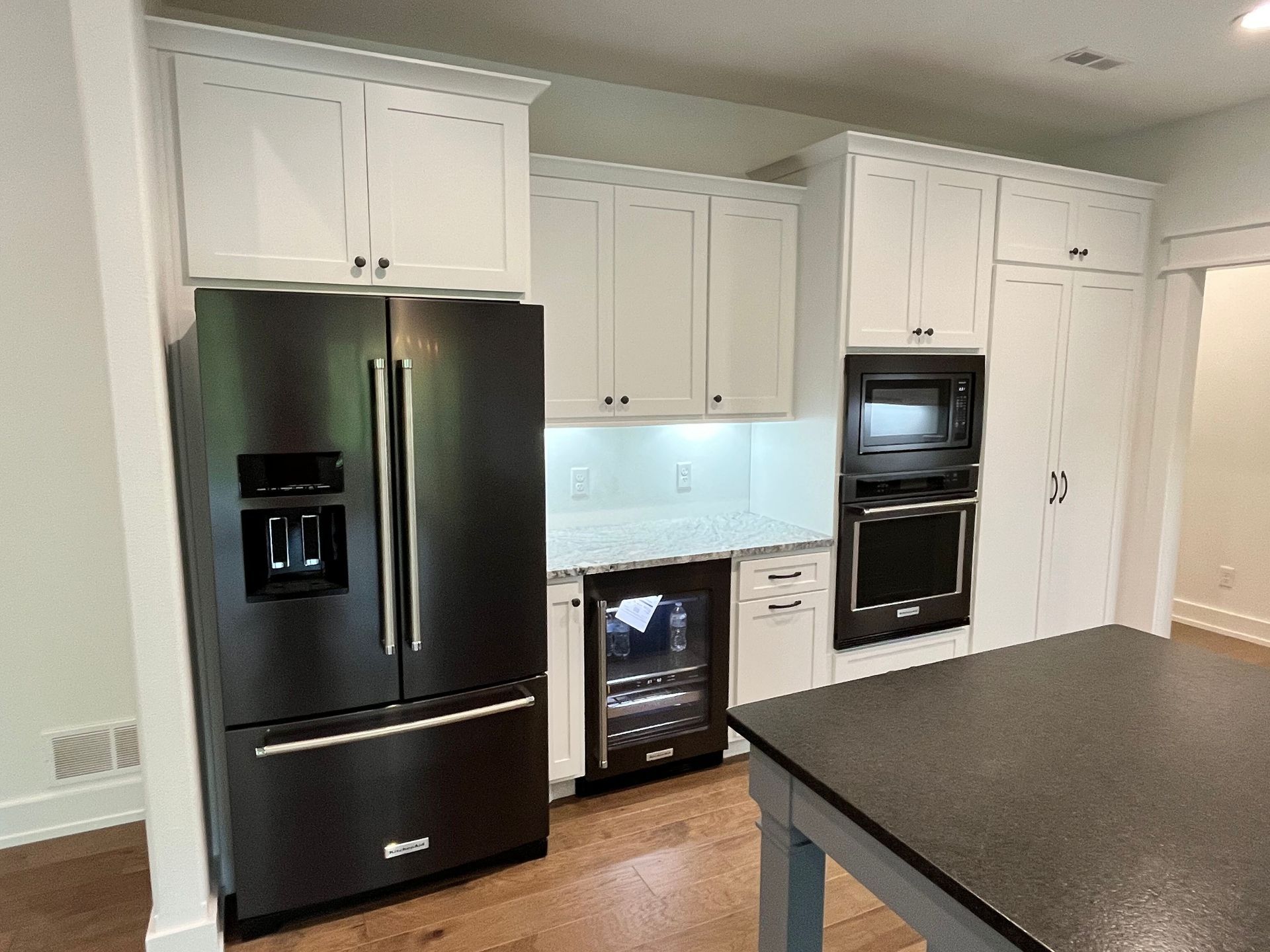 Modern kitchen with black appliances, white cabinets, and a dark countertop