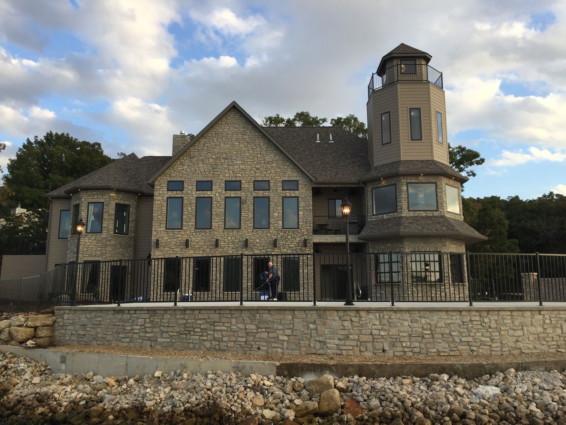 Stone mansion with turret and stone wall under a cloudy sky