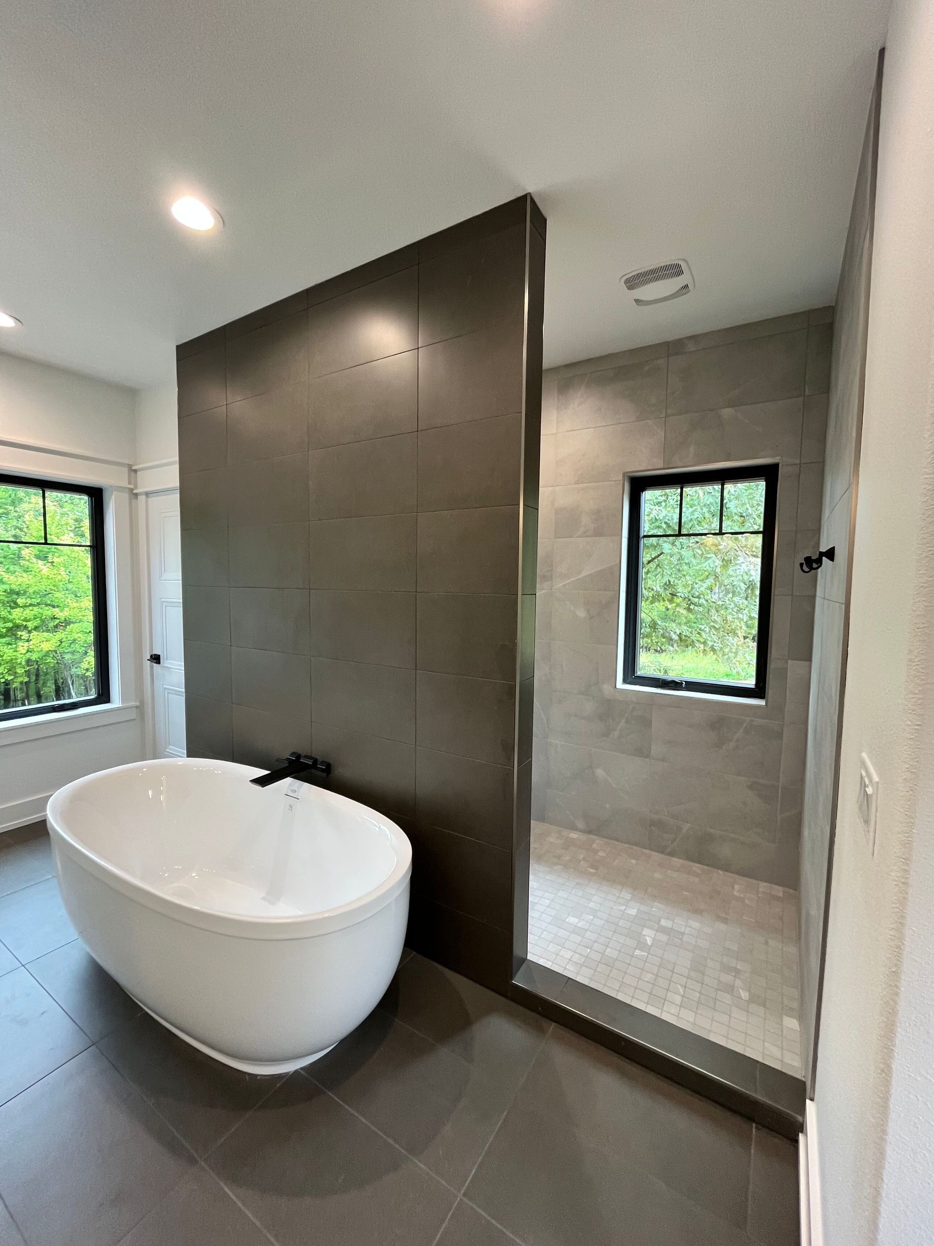 Modern bathroom with freestanding tub, large walk-in shower, and gray tile walls