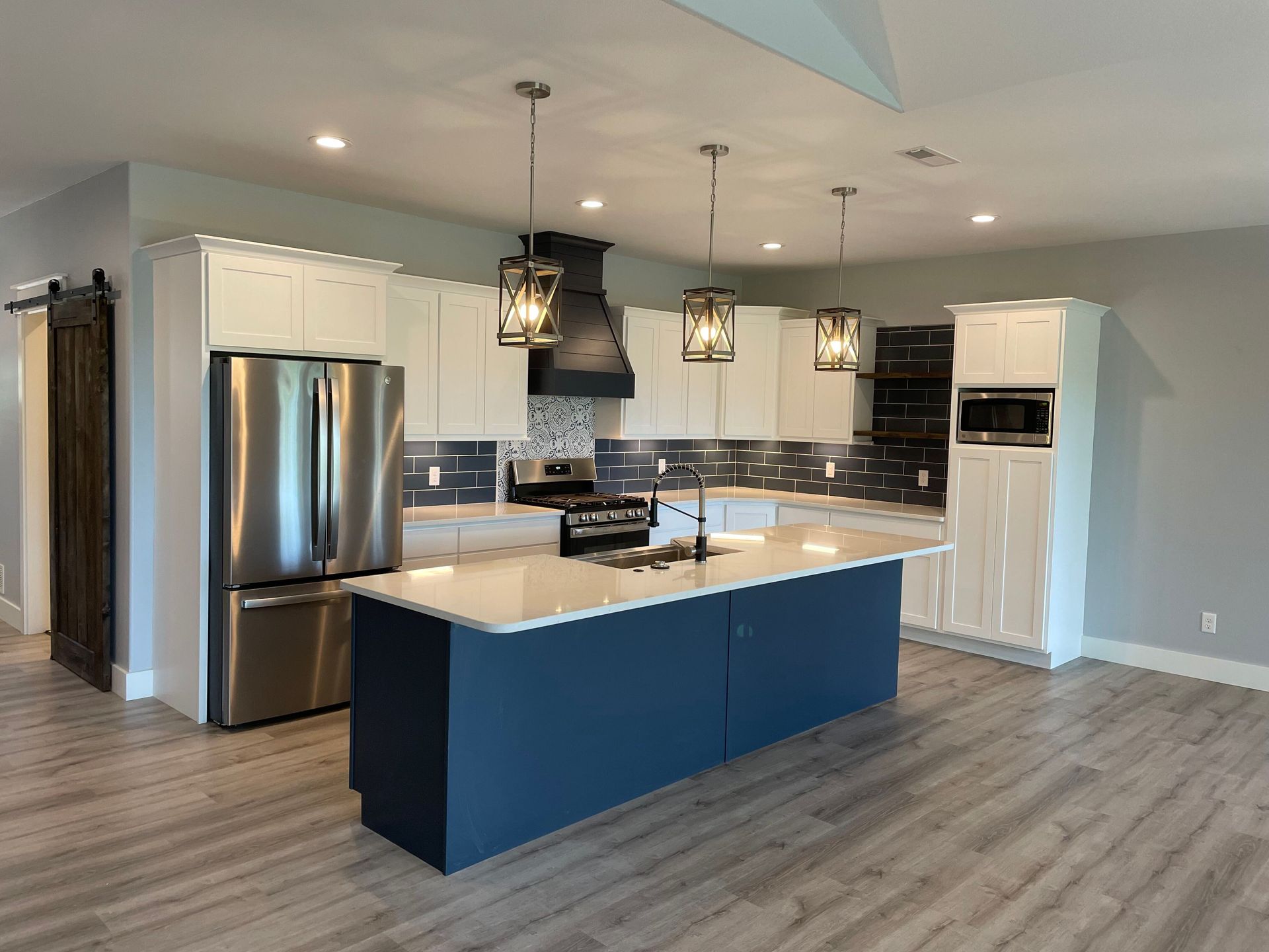 Modern kitchen with blue island, stainless steel appliances, and pendant lights